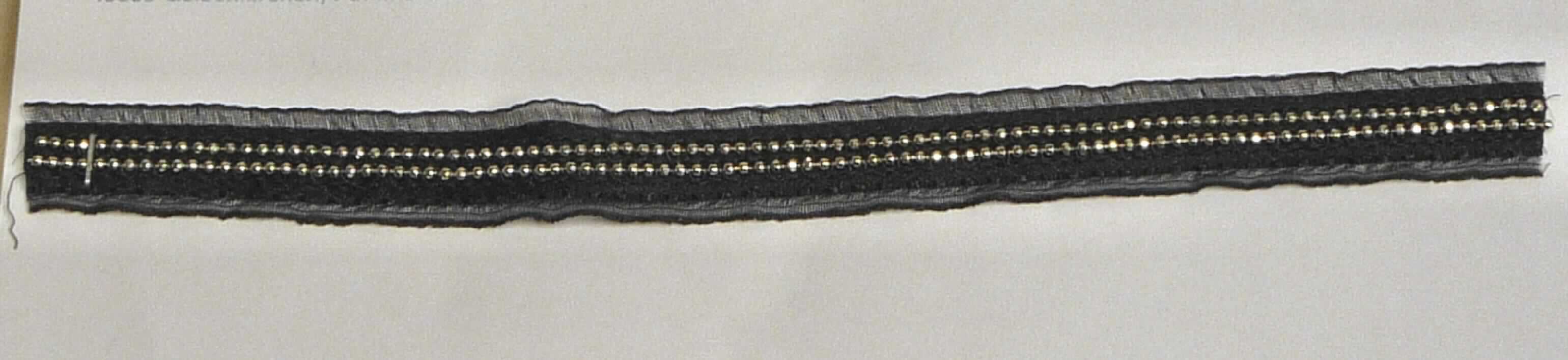 Stickerei, sog. Zierband für Bekleidung, Art. 125423, Foto siehe Anlage,
- als Streifen, laut Antrag auf Rollen mit einer Länge von ca. 100 m,
- mit einer Breite von ca. 1,5 cm,
- keine Ätzstickerei oder Stickerei mit herausgeschnittenem Grund,
- ohne Hinweise auf Handarbeit,
- mit einem Stickgrund aus Geweben aus laut Antrag 100 % Polyester (synthetische Chemiefasern),
- auf diesen Grund sind zwei Kugelketten aus augenscheinlich unedlem Metall aufgestickt,
- laut Antrag mit einem Wert von mehr als 17,50 EURO je kg Eigengewicht.

"Stickerei als Streifen, andere als in der Unterposition 5810 10 genannte, aus Chemiefasern, mit einem Wert von 
 mehr als 17,50 EURO je kg Eigengewicht, nicht handgearbeitet"