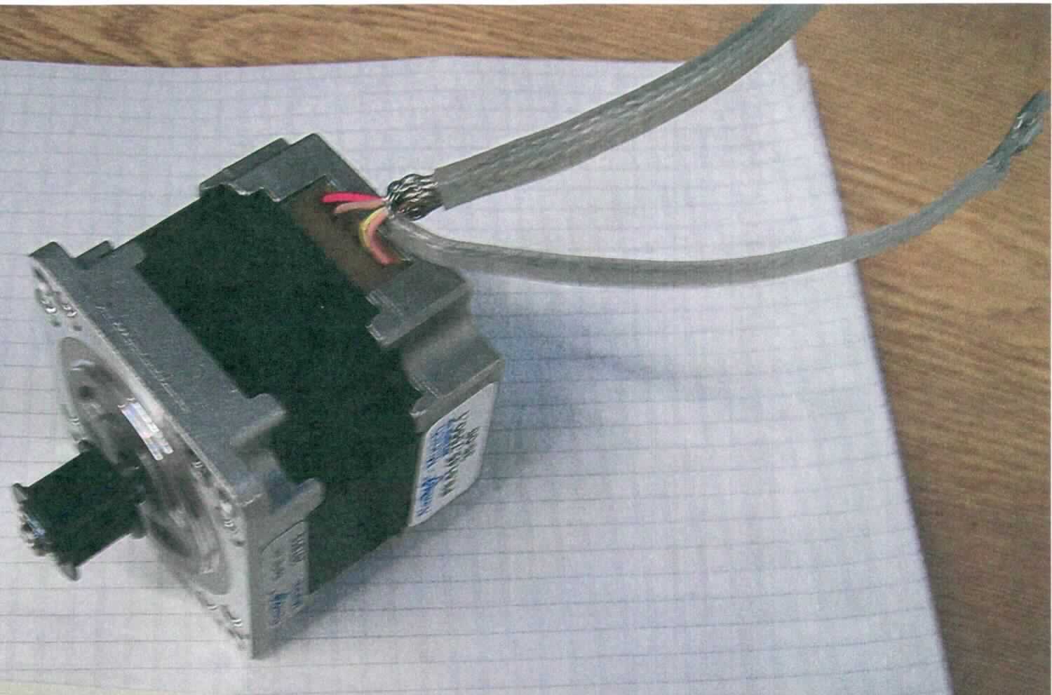 Schrittmotor,
Gleichstrommotor 4,5 W, Elektromotor (Hauptfunktion) in Form eines Synchronmotors (Schrittmotor), in einem quaderförmigen Motorgehäuse (Abmessungen: 56,4 x 56,4 x 49 mm), in Kombination mit einer Welle mit einem Zahnriemenrad (Z=10), mit zwei Anschlusskabeln versehen, mit einer Leistung von ca. 4,5 W bei einer Versorgungsspannung von 1,25 V bei einer Stromstärke von 3,5 A, zur Verwendung in einem Digitizer "CR 35-X"  als Motor zum Öffnen der Röntgenkassette in einer Kassetteneinheit.

Das Erzeugnis ist als "Elektromotor mit einer Leistung von 37,5 W oder weniger, Synchronmotor mit einer Leistung von 18 W oder weniger, nicht für bestimmte Luftfahrzeuge - Schrittmotor" einzureihen.

Siehe Abbildung.