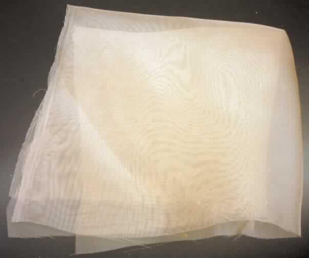 Gewebe, sog. Microgaze-Haube, Foto siehe Anlage,
- soll als Unterbau (Montur) einer Perücke verwendet werden, auf der Haare verknüpft werden,
- aus ungezwirnten, nicht hochfesten, nicht texturierten Garnen aus synthetischen Filamenten
  (lt. Antrag Polyester),
- in Leinwandbindung,
- gefärbt,
- in quadratischer Form zugeschnitten (nicht konfektioniert); in den Abmessungen: ca. 34 cm x 34 cm,
- leicht dreidimensional gewölbt gearbeitet,
- keine unvollständige/unfertige Perücke der Position 6704, weil die Montur noch nicht die wesent-
  lichen Beschaffenheitsmerkmale der vollständigen/fertigen Ware aufweist; wird als Teil einer 
  Perücke nicht vom Warenkreis der Position 6704 erfasst,
- aufgrund der Beschaffenheit, der Abmessungen und des Verwendungszweckes kein Haarnetz der
  Position 6505, 
- stellt sich aufgrund der Beschaffenheit und des Materials auch nicht als konfektioniertes
  Netz der Position 5608 dar.

"Gewebe aus Garnen aus synthetischen Filamenten, andere als in den Unterpositionen 5407 10 bis
 5407 5400 genannte, mit einem Anteil an nicht texturierten Polyester-Filamenten von mehr 85 GHT,
 gefärbt"