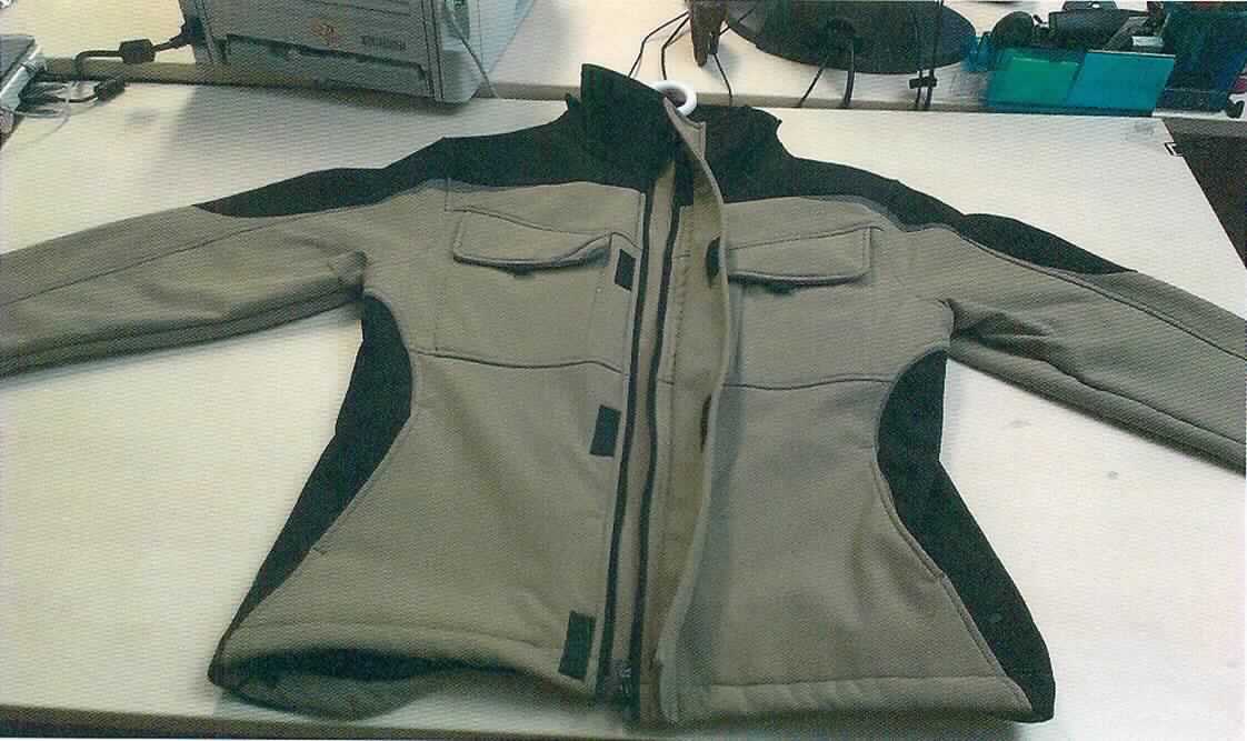 Blouson, sog. Softshell-Jacke grau/schwarz, Art. BWSJ-GRS, Größe L, Foto siehe Anlage,
- aus ca. 1,7 mm dicken, dreilagigen Flächenerzeugnissen der Position 5903 mit einer Außenlage aus verschie-
  denen, einfarbigen Geweben, einer Zwischenlage aus einer Folie aus Kunststoff (laut Antrag: Polyurethan) und 
  einer Innenlage aus einfarbigen, einseitig gerauten Gewirken; alle Spinnstoffe aus laut Antrag 100 % synthe-
  tischen Chemiefasern,
- teilweise leicht gefüttert,
- über die Taille reichend (Rückenlänge: ca. 75 cm),
- mit einem Stehkragen, mit einer durch Reißverschluss abtrennbaren Kapuze mit Tunnelzug,
- vorn mit einer durchgehenden Öffnung mit einem bis in die Kragenspitzen reichenden Reißverschluss, verdeckt 
  von einer Patte mit Klettverschluss von links auf rechts (Männerkleidung),
- mit langen Ärmeln, die über den unteren Rand des Kleidungsstücks hinausreichen; an den Ärmelenden mit 
  Klettriegeln zu verengen,
- vorn mit zwei aufgesetzten Brusttaschen mit Patte und Klettverschluss sowie mit zwei eingesetzten Taschen mit 
  Reißverschluss unterhalb der Taille,
- mit reflektierenden Streifen und Paspeln versehen,
- am unteren Rand mit einem Tunnelzug zu verengen,
- erfüllt die Merkmale zur Einreihung als Blouson, somit keine Jacke,
- die Gewebe der Außenlage verleihen dem Flächenerzeugnis insbesondere im Hinblick auf das äußere 
  Erscheinungsbild seinen wesentlichen Charakter.

"Kleidung (Blouson), aus Erzeugnissen der Position 5903, aus Geweben, für Männer"