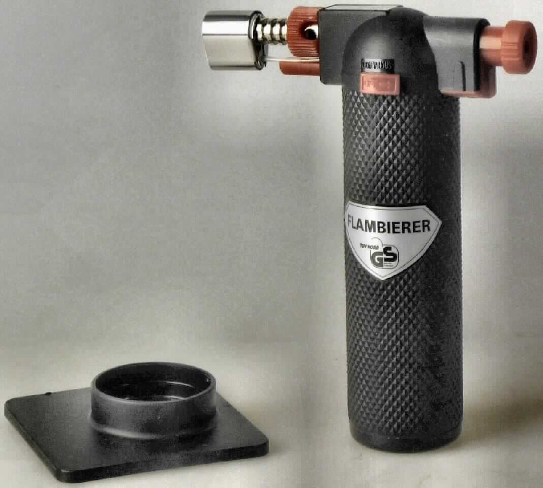 Flambierer

- mit freiem Arm zu handhabendes, nicht elektrisch betriebenes Erzeugnis zur Verwendung im Haushalt 
  und in der Küche, z. B. zum Gratinieren von Speisen

- einem in etwa pistolenförmigen Kunststoffgehäuse mit glatter Standfläche, welches einen nachfüllbaren
  Gasbehälter mit einem Einfüllventil, eine Flammendüse, ein Gas- und ein Luftzufuhrregulierungsrädchen,
  einen Druckschalter zum Starten der Flamme sowie einen Feststellschieber für die Dauerfunktion aufweist

- gemeinsam mit einer Bedienungsanleitung und einem Standfuß aus Kunststoff in einer Blisterverpackung 
  für den Einzelverkauf aufgemacht

Abbildung siehe Anlage. 

Derartige Erzeugnisse gehören als "Lötlampen und dergleichen" zum TARIC-Code 8205 6000 00.