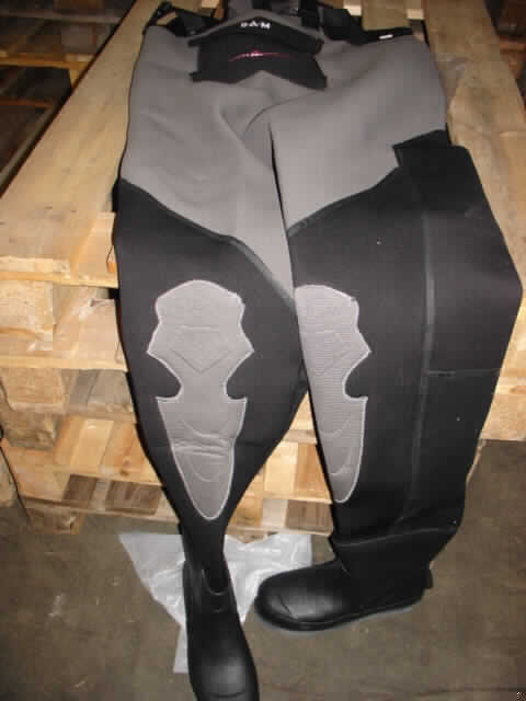 Zusammengesetzte Ware (overallähnliche Kleidung aus Gewirken der Position 5906 und ein angesetztes
Paar Schuhe), sog. Heavy Duty Neopren-Wathose, Artikel 8709-114, in Erwachsenengröße, Fotos siehe Anlage,
- overallähnliche Kleidung:
-- ärmellos; annähernd bis zu den Achseln reichend; mit längenverstellbaren Trägern über den Schultern,
-- laut Untersuchungsergebnis:
--- bestehend aus einem dreilagigen Flächenerzeugnis mit einem Quadratmetergewicht von 1239 g,
---- mit einer Lage aus Zellkautschuk (laut Antrag Neopren), die beidseitig mit nicht nur der Verstärkung
     dienenden Gewirken aus laut Etikett Nylon (synthetische Chemiefasern) ausgestattet ist (kautschutiertes
     Gewirke der Position 5906),
- Schuhe:
-- den Knöchel bedeckende Stiefel mit Oberteil aus laut Antrag PTE-Gummi und Laufsohlen aus Filz (Spinnstoff),
- nach dem Wert, dem Umfang (Anteil des Körpers, der durch die Bestandteile bedeckt/geschützt wird) und 
  nach der Bedeutung in Bezug auf die Verwendung der Ware (Stiefel: Schutz vor Nässe, overallähnliche Kleidung:
  Schutz vor Nässe / Warmhalten von Körperteilen) ist die overallähnliche Kleidung als charakterbestimmend 
  anzusehen.

"Zusammengesetzte Ware
 aus Kleidung aus Gewirken der Position 5906 (charakterbestimmend)
 und anderen Schuhen (Schuhe mit Laufsohle aus Spinnstoffen)"