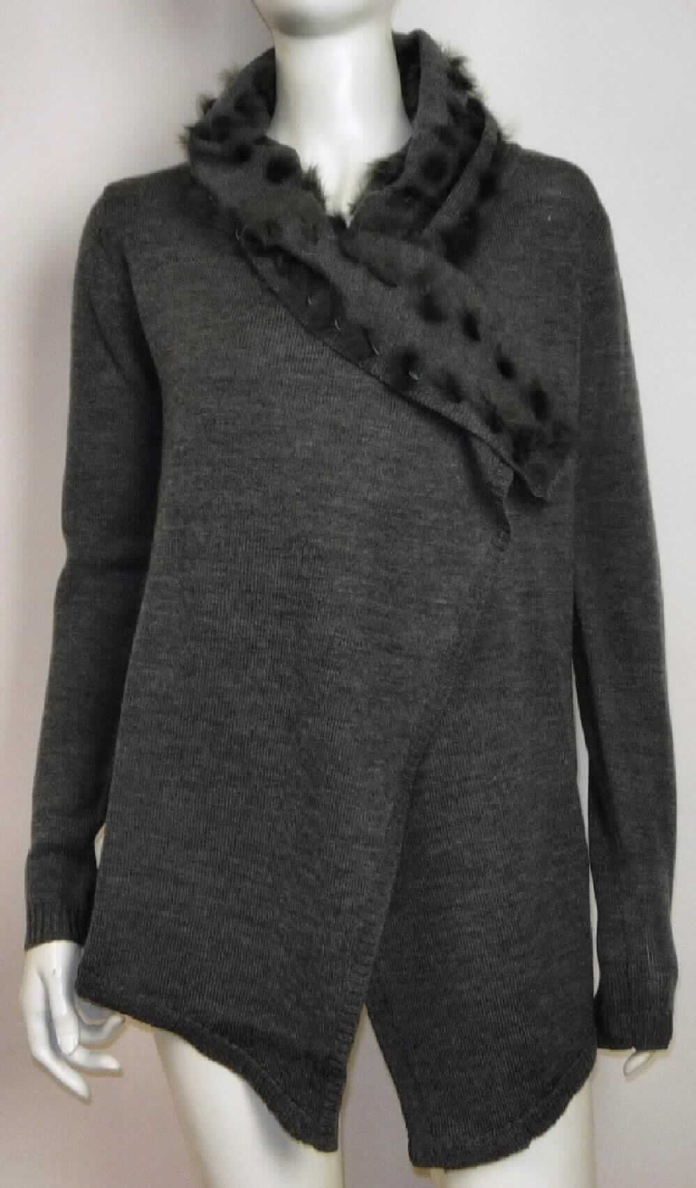 Strickjackenähnliches Kleidungsstück, sog. Cardigan für Frauen, Art. W04067, Größe S, Foto siehe Anlage,
- aus ca. 1,5 mm dicken, buntgewirkten Gewirken (melierte Garne) aus laut Antrag Merinowolle,
- bis etwa zum Schritt reichend (Rückenlänge: ca. 69 cm),  
- ungefüttert,
- mit einem Umlegekragen, der sich auf der Rückseite zu einer Kapuze erweitert, mit einem einfachen Besatz 
  aus laut Antrag Angorafell,
- vorn mit einer durchgehenden Öffnung ohne Verschluss,
- ohne Hinweise auf den Trägerkreis (unisex),
- mit langen Ärmeln, an den Ärmelenden mit gerippt gewirkten Bündchen,
- mit verlängerten Vorderteilen, die bis zu ca. 11 cm über den unteren Rand hinausreichen (flachliegend gemessen), 
- am unteren Rand mit gerippt gewirktem Bündchen,
- weist weder aufgrund des Schnitts noch aufgrund der Ausstattung eine Formfestigkeit auf, somit keine Ware
  der Position 6104,
- wird im Allgemeinen nicht über jeder anderen Kleidung und zum Schutz gegen das Wetter getragen, somit kein
  Kleidungsstück der Position 6102.

"Strickjackenähnliches Kleidungsstück, aus Gewirken, aus Wolle, für Frauen"