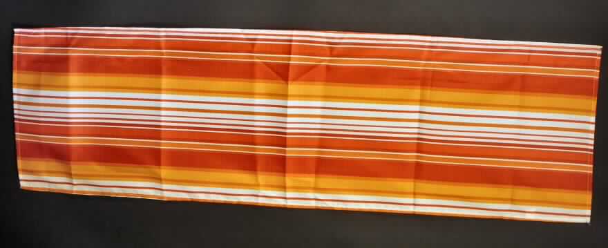 Tischwäsche (Tischläufer), sog. Tischläufer, 4 sort. Polyester, Foto siehe Anlage,
- aus ca. 0,2 mm dicken, bedruckten Geweben aus lt. Antrag 100 % Polyester (synthetische Chemiefasern),
- rechteckig; lt. Antrag mit einer Länge von 140 cm und einer Breite von 40 cm,
- an den Rändern gesäumt (somit konfektioniert),
- wird üblicherweise gewaschen und kennzeichnet sich insbesondere aufgrund des Materials und des 
  Verwendungszwecks als Tischwäsche,
- in einem Polybeutel für den Einzelverkauf aufgemacht.

"Tischwäsche, aus Spinnstoffen, aus Geweben, aus Chemiefasern"