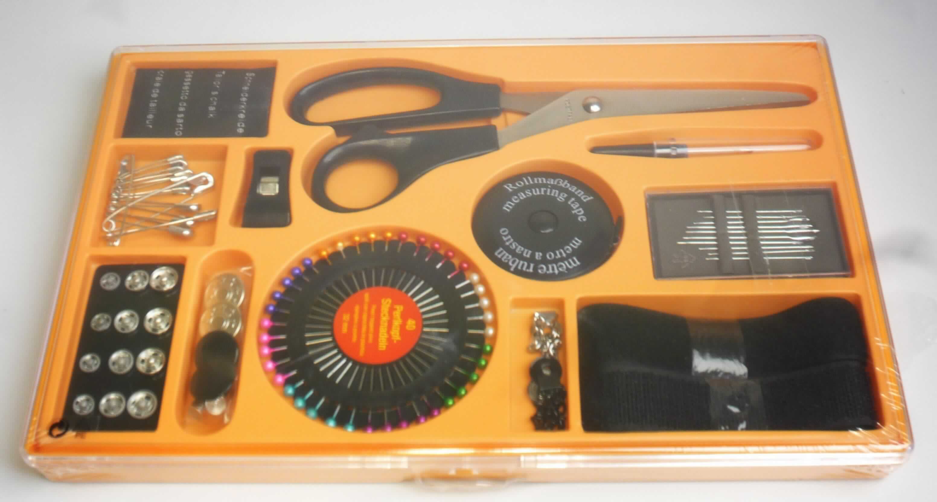"Schneider-Box"; Warenzusammenstellung in Aufmachung für den Einzelverkauf, 
bestehend aus 

- 1 Schneider-Schere (Pos 8213)
  bestehend aus zwei um einen Stift x-förmig beweglich gelagerten, geraden
  Scherenblättern mit geradem Schliff aus unedlem Metall, die unlösbar in Griffe aus 
  Kunststoff eingesetzt sind; die Griffenden der Schneider-Schere sind zur leichteren 
  Handhabung jeweils zu einer Öse zum Durchstecken des Daumens oder eines anderen 
  Fingers ausgearbeitet
- 1 Schneiderkreide
- 1 Nahttrenner
- 1 Textilklammer
- 1 Rollmaßband
- 4 Paar Jeans Knöpfe
- 2 Mantelaufhänger
- 10 Nähnadeln (Pos 7319)
- 12 Sicherheitsnadeln (Pos 7319)
- 40 Perlkopfstecknadeln (Pos 7319)
- 12 Paar Druckknöpfe
- 1 Klett-Verschlussband

- zum Ausüben von Näh- und Schneiderarbeiten

- die Warenzusammenstellung ist vollständig in einer zum dauernden Gebrauch geeigneten 
  Kunststoffbox, mit passgenauen Aussparungen für die einzelnen Bestandteile, aufgemacht; 
  die Kunststoffbox ist zusätzlich in einer Kunststofffolie verpackt

- hinsichtlich der Menge bilden die Nadeln (Pos 7319), hinsichtlich des Wertes bildet die 
  Schere (Pos 8213) den charakterverleihenden Bestandteil, andere Kriterien sind nicht 
  geeignet; da keine der gleichermaßen in Betracht kommenden Positionen den 
  charakterverleihenden Bestandteil der Warenzusammenstellung bildet, ist diese in die 
  zuletzt genannte dieser Positionen einzureihen (Pos 8213)

Abbildung siehe Anlage.

Derartige Erzeugnisse gehören als "Scheren mit arbeitendem Teil aus unedlem Metall" zur 
Codenummer 8213 0000 00 0 des Zolltarifs.