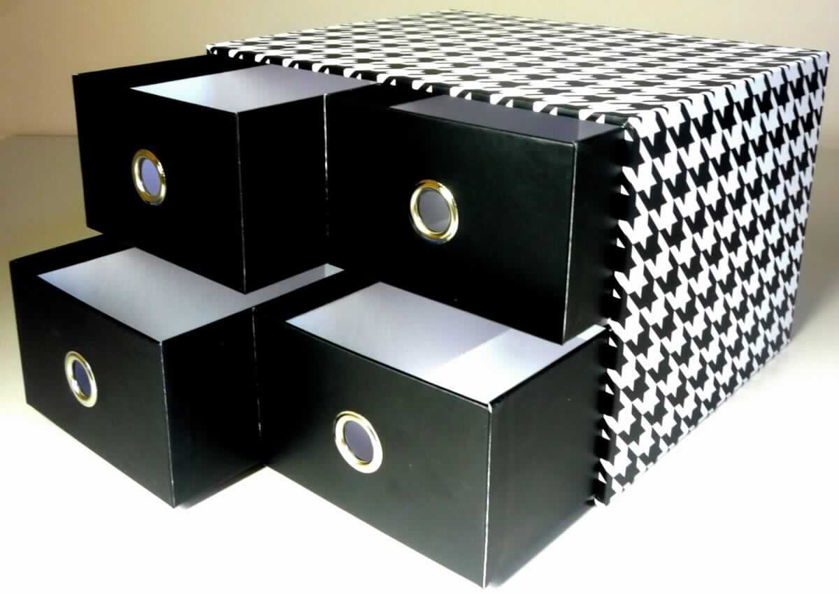 Bei der als "Schubladenbox mit 4 Schüben aus Papier" bezeichneten Ware handelt es sich nach dem vorgelegten Warenmuster um ein etwa 25,4 x 20,9 x 16,9 cm (L x B x H) großes, stabiles Raumerzeugnis in Form eines an der Stirnseite offenen Quaders aus Pappe. Auf der Innenseite ist es mit weißem Papier, auf der Außenseite mit Hahnentrittmuster bedrucktem und mit Kunststofffolie überzogenem Papier beklebt. Es ist mittig mit einem Einlegeboden aus Pappe versehen. In das Erzeugnis sind vier jeweils etwa 20,4 x 12,3 x 7,7 cm 
(L x B x H) große Schubkästen eingesteckt, die aus den gleichen Materialien gefertigt sind, wobei die Kästen auf der Außenseite jeweils mit einem mit Kunststofffolie überzogenen, schwarzen Papier beklebt sind. Sie sind an der Stirnseite jeweils mit einem kreisrunden Loch (Durchmesser etwa 1,7 cm) mit einer Randverstärkung aus unedlem Metall versehen, welches ein leichteres Herausziehen der Schubkästen ermöglicht.

Abbildung siehe Anlage.

Derartige Waren gehören als "Pappwaren von der in Büros, Geschäften und dergleichen verwendeten Art" zur Codenummer 4819 60 00 00 0 des Zolltarifs, da ihr wesentlicher Charakter nach Umfang und im Hinblick auf die Bedeutung in Bezug auf die Verwendung durch die Papier- und Pappanteile bestimmt wird.
