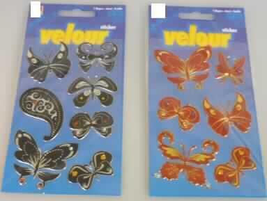 Bei den als "Velours-Sticker" bezeichneten Waren handelt sich um unterschiedlich große, rote, in Form von Schmetterlingen zugeschnittene scherstaubbeflockte, selbstklebende Folien aus Kunststoffen im Sinne der Anmerkung 1 zu Kapitel 39. Die flachliegenden, selbstklebenden Erzeugnisse sind jeweils verziert mit kleinen bunten Strasssteinchen aus Kunststoffen und einzeln abziehbar auf einer transparenten Trägerfolie (ca. 8 x 13 cm) aufgebracht.

Jeweils sechs "Velours- Sticker" sind in einer Polytüte auf einem Pappträger für den Einzelverkauf aufgemacht.

Sie werden als "selbstklebende Flacherzeugnisse aus Kunststoffen, weiter bearbeitet als nur mit Oberflächenbearbeitung oder anders als nur quadratisch oder rechteckig zugeschnitten" von der Codenummer 3919 9010 00 0 erfasst.