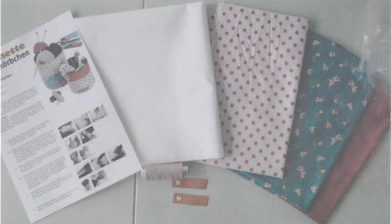 Handarbeitsset, sog. Näh-Set, Art.-Nr. 80571, Foto siehe Anlage,
- Warenzusammenstellung, bestehend aus drei Geweben, zwei Etiketten, einem Garn, Vliesstoff und einer 
  Anleitung; gemeinsam in einem Polybeutel für den Einzelverkauf aufgemacht und zur Befriedigung eines 
  speziellen Bedarfs zusammengestellt, 
- Gewebe:
-- rechteckig zugeschnitten; zwei Gewebe mit den Abmessungen von lt. Antrag 30 cm x 75 cm und ein Gewebe 
   mit den Abmessungen von lt. Antrag 30 cm x 150 cm,
-- lt. Antrag aus 100 % Baumwolle,
-- in Leinwandbindung,
-- bedruckt (nicht nach dem Batik-Verfahren handbedruckt),
-- mit einem Quadratmetergewicht von ca. 140 g,
-- nicht auf Handwebstühlen hergestellt,
- Etiketten:
-- rechteckig; mit einer Länge von ca. 5,5 cm und einer Breite von ca. 1,5 cm,
-- aus buntgewebten Geweben aus lt. Antrag 100 % Polyester,
-- mit Kanten, die durch Heißschneiden gegen Ausriefeln gesichert sind,
-- nicht bestickt,
- Garn:
-- auf einer Papphülse aufgemacht; mit einer Länge von lt. Antrag 500 m,
-- gezwirntes Garn aus lt. Antrag 100 % Polyester,
-- mit einer Z-Drehung als letzter Drehung,
- Vliesstoff:
-- rechteckig zugeschnitten; mit einer Länge von ca. 100 cm und einer Breite von ca. 90 cm,
-- lt. Antrag aus 60 % Polyester und 40 % Viskose,
-- mit einem Quadratmetergewicht von ca. 68 g,
-- einseitig mit Schmelzkleber bestrichen,
- Anleitung:
-- im DIN A4-Format,
-- in Form eines mit Texten und Abbildungen bedruckten Blattes, 
- dient der Herstellung von zwei Aufbewahrungskörbchen,
- die Gewebe verleihen der Warenzusammenstellung insbesondere im Hinblick auf die Bedeutung in Bezug auf die 
  Verwendung ihren wesentlichen Charakter.

"Gewebe aus Baumwolle, mit einem Anteil an Baumwolle von mehr als 85 GHT und einem Quadratmetergewicht
 von weniger als 200 g, bedruckt, in Leinwandbindung, mit einem Quadratmetergewicht von mehr als 100 g,
 nicht auf Handwebstühlen hergestellt, nicht nach dem Batik-Verfahren handbedruckt"