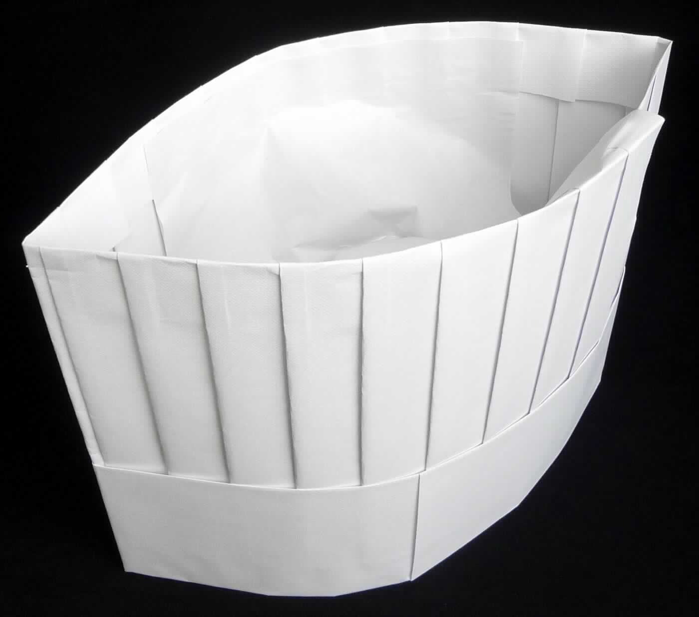 Kopfbedeckung, sog. Kochmütze Le Chef, Abbildung siehe Anlage, 
- aus Papierzuschnitten zusammengeklebt, 
- flachgefaltet, geprägt, mit einer Länge von ca. 28 cm und einer Höhe von ca. 20 cm, 
- mit einem Schweißband aus Vliesstoff, 
- oben teilweise geschlossen, 
- wird zu hygienischen Zwecken z.B. in der Lebensmittelbranche getragen.

"Andere Kopfbedeckung (Kochmütze) aus Papier"