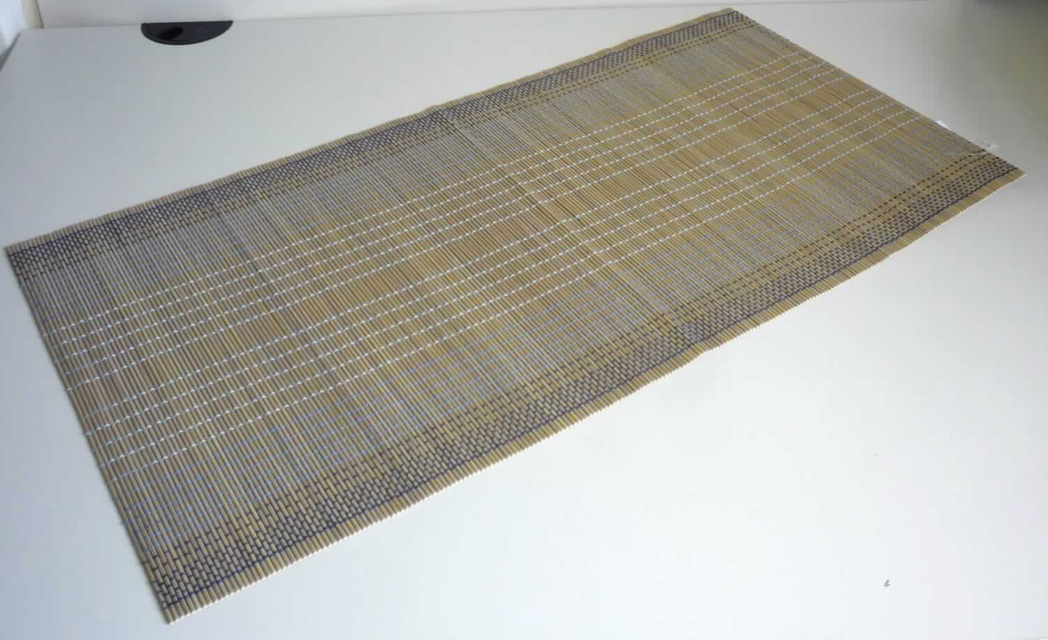 Nach den Antragsangaben und dem vorliegenden Warenmuster handelt es sich bei dem sog. "Bambus Tischläufer, Art. 288074, Dessin 01" um eine ca. 40 x 80 cm große Matte. Das Erzeugnis besteht charakterverleihend aus biegsamen, ca. 3 mm breiten, beigefarbenen Bambusstäbchen (Flechtstoffe im Sinne der Anmerkung 1 zu Kapitel 46), die parallel nebeneinander gelegt und mittels quer laufenden Haltefäden aus musterbildend verarbeiteten Spinnstoffgarnen (in drei Blautönen) in Flächenform miteinander verbunden sind.
Die Ware ist als 4er Set in einer Aufmachung für den Einzelverkauf verpackt.

Zolltarifrechtlich handelt es sich um "Flechtstoffwaren, parallel aneinander gefügt. Matten aus pflanzlichen Stoffen, aus Bambus, andere als aus Geflechten oder ähnlichen Waren aus Flechtstoffen".