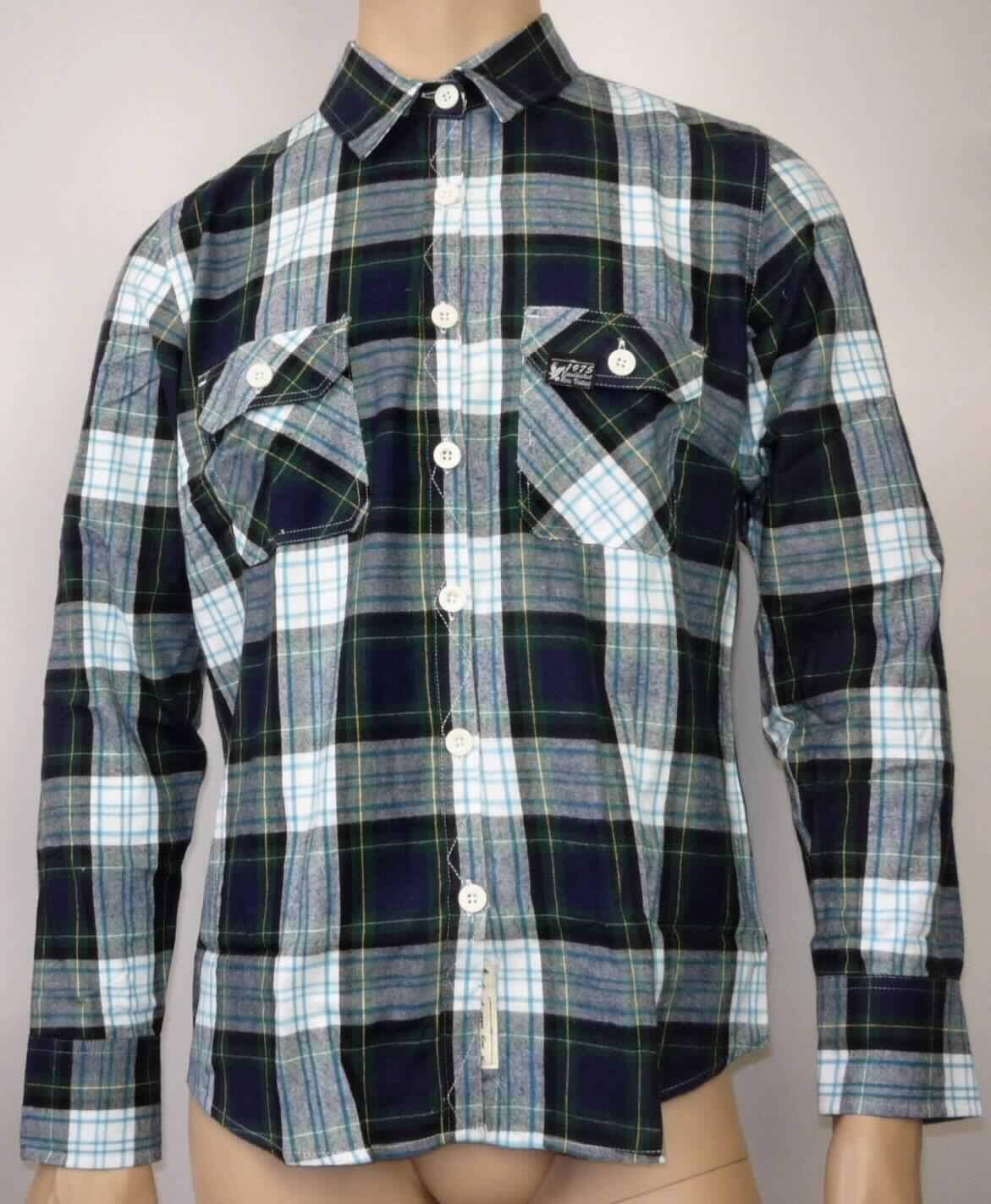 Hemdbluse, sog. Lumberjacke Shirt woman, navy, gemustert, Art. 33-5006-20, Größe L, Foto siehe Anlage,
- aus etwa 0,6 mm dicken, buntgewebten (karierten) Geweben aus laut Antrag 100 % Baumwolle,
- über die Taille reichend (Rückenlänge: etwa 73 cm),
- mit Umlegekragen,
- im Rücken mit Schultersattel,
- vorn mit einer durchgehenden Öffnung mit Knopfverschluss von rechts über links (Frauenkleidung),
- mit langen Ärmeln mit manschettenartigen Abschlüssen; auf der Innenseite mit einer angenähten Lasche, 
  im Bereich des Oberarms mit einem Knopf zum Fixieren der aufgerollten Ärmel,
- mit zwei aufgesetzten Brusttaschen mit Patte und Knopfverschluss,
- den Hemden für Männer entsprechend zugeschnitten,
- am unteren, abgerundeten Rand durch Umschlagen und Festnähen gesäumt.

"Hemdbluse, aus Geweben, für Frauen, aus Baumwolle, nicht nach dem Batikverfahren handbedruckt"