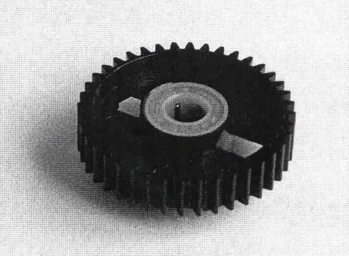 Geradstirnrad, siehe Abbildung,
selbsttätig schaltende Wellenkupplung bestehend aus einem Zahnrad mit einem Durchmesser von ca. 42 mm bei einer Dicke von bis zu 14,35 mm aus Kunststoff mit integriertem Freilauf, mit speziellen Klemmnadeln ausgerüstet, mit einer Mittelöffnung von ca. 8 mm. 
Zur Befestigung auf einer Welle in einem Drucker.

Die Ware ist als "Schaltkupplung (Wellenkupplung), nicht aus Eisen oder Stahl gegossen, nicht für zivile Luftfahrzeuge" einzureihen.