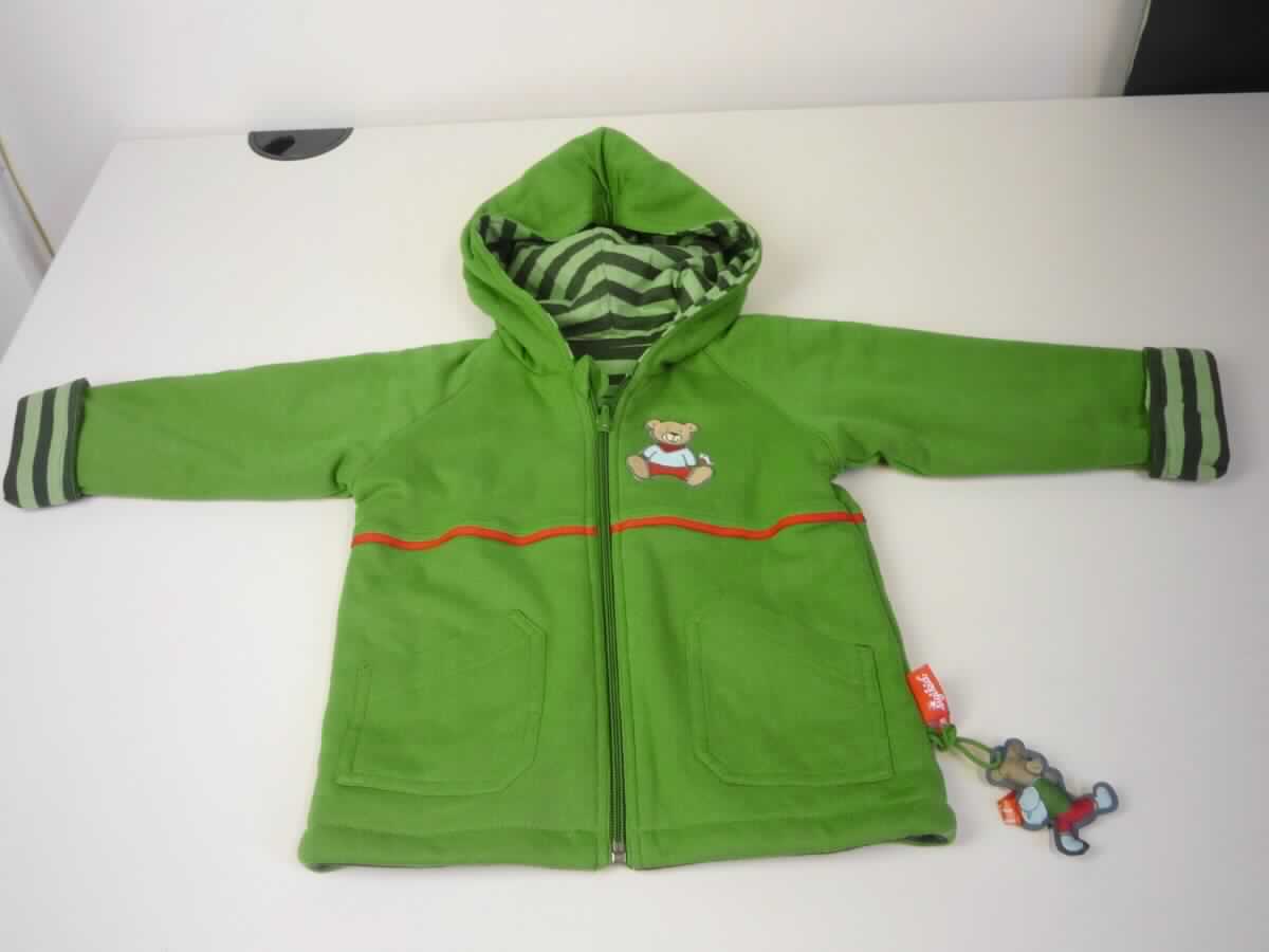 Anorak, sog. Kinderbekleidung, Artikel 156907, Größe 92, Foto siehe Anlage,
- gemeinsam mit einem an einer Schlaufe befestigten Deko-Anhänger in einem Polybeutel verpackt; 
  der Deko-Anhänger ist geringwertig und im Hinblick auf die Verwendung als unbedeutend zu betrachten, 
  er ändert das Wesen der Hauptware nicht und ist deshalb wie diese einzureihen,
- als Wendekleidungsstück von beiden Seiten zu tragen,
- mit Schauseiten aus ca. 0,5 mm dicken, einfarbigen bzw. buntgewirkten Gewirken aus lt. Antrag 
  100 % Baumwolle,
- wattiert gefüttert,
- über den Schritt reichend (Rückenlänge: ca. 41,5 cm), 
- mit einer angesetzten Kapuze,
- vorn mit einer durchgehenden Öffnung mit Reißverschluss, mit einer kurzen Überlappung von rechts 
  über links bzw. von links über rechts, je nach Tragart des Wendekleidungsstückes (unisex),
- mit langen Ärmeln; an den Ärmelenden durch Umschlagen und Festnähen gesäumt, 
- vorn mit zwei eingesetzten Taschen auf der buntgewirkten und zwei aufgesetzten Taschen auf der 
  einfarbigen Seite unterhalb der Taille,
- mit aufgenähten Applikationen verziert, 
- am unteren Rand durch Umschlagen und Festnähen gesäumt,
- wird im Allgemeinen über jeder anderen Kleidung und zum Schutz gegen das Wetter getragen. 

"Anorak, aus Gewirken, für Mädchen, aus Baumwolle"