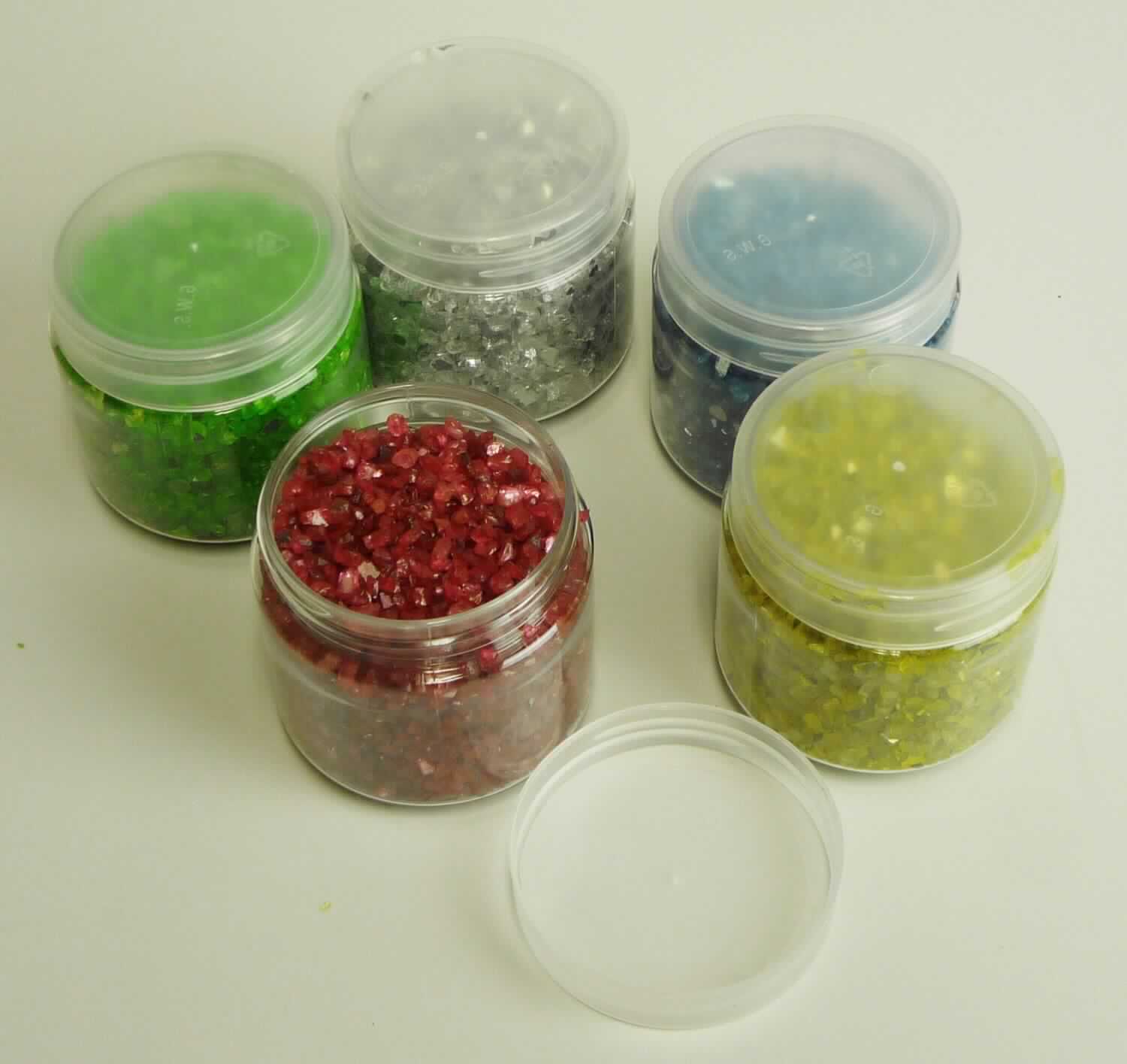 Angaben: 
Spiegelgranulat; Zerkleinertes, eingefärbtes Spiegelglas; zur Verwendung als Dekorationsmaterial für Vasen, Schalen etc. 

Warenbeschaffenheit: 
Unregelmäßig geformtes, gelbes, graues, grünes, rotes und blaues Granulat mit den Abmessungen von ca. 2 bis 8mm, wobei überwiegend Granulat mit einer Größe von < 4mm vorhanden ist, bei 1000°C als farblose Schmelze vorliegend, verpackt in fünf Musterkunststoffdosen zu je 280g.

Befund: 
Anderes Glas in Form von Pulver, Granalien, Schuppen oder Flocken.
