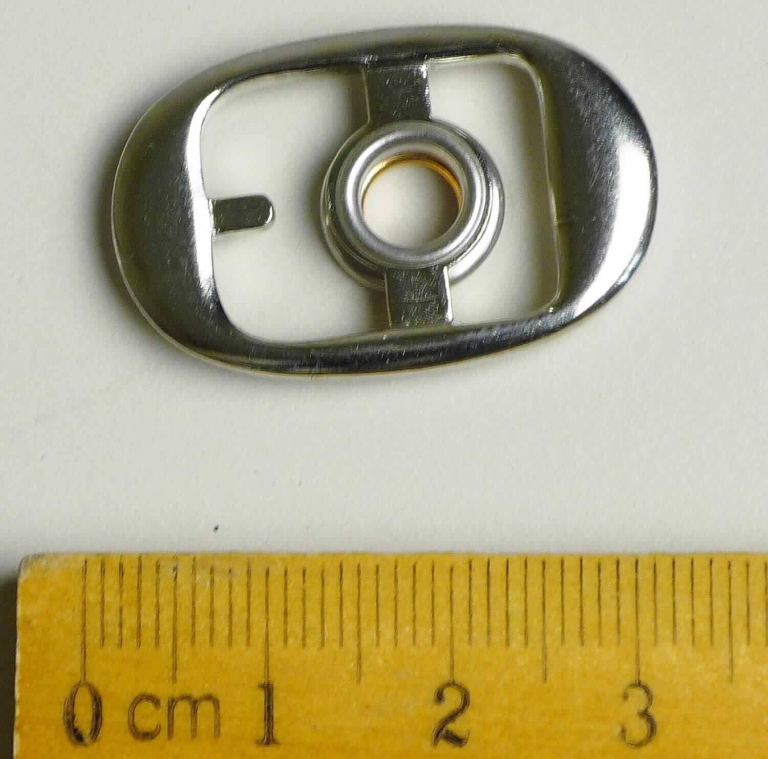 Bei der aus gewalztem Stahl bestehenden Schnalle mit abgerundeten Ecken (Breite ca. 20 mm und Länge ca. 30 mm) handelt es sich um ein erkennbares Teil eines Druckknopfs, der als Schuhverschluss eingesetzt wird.

Die Ware wird als erkennbares Teil eines Druckknopfs eingereiht.