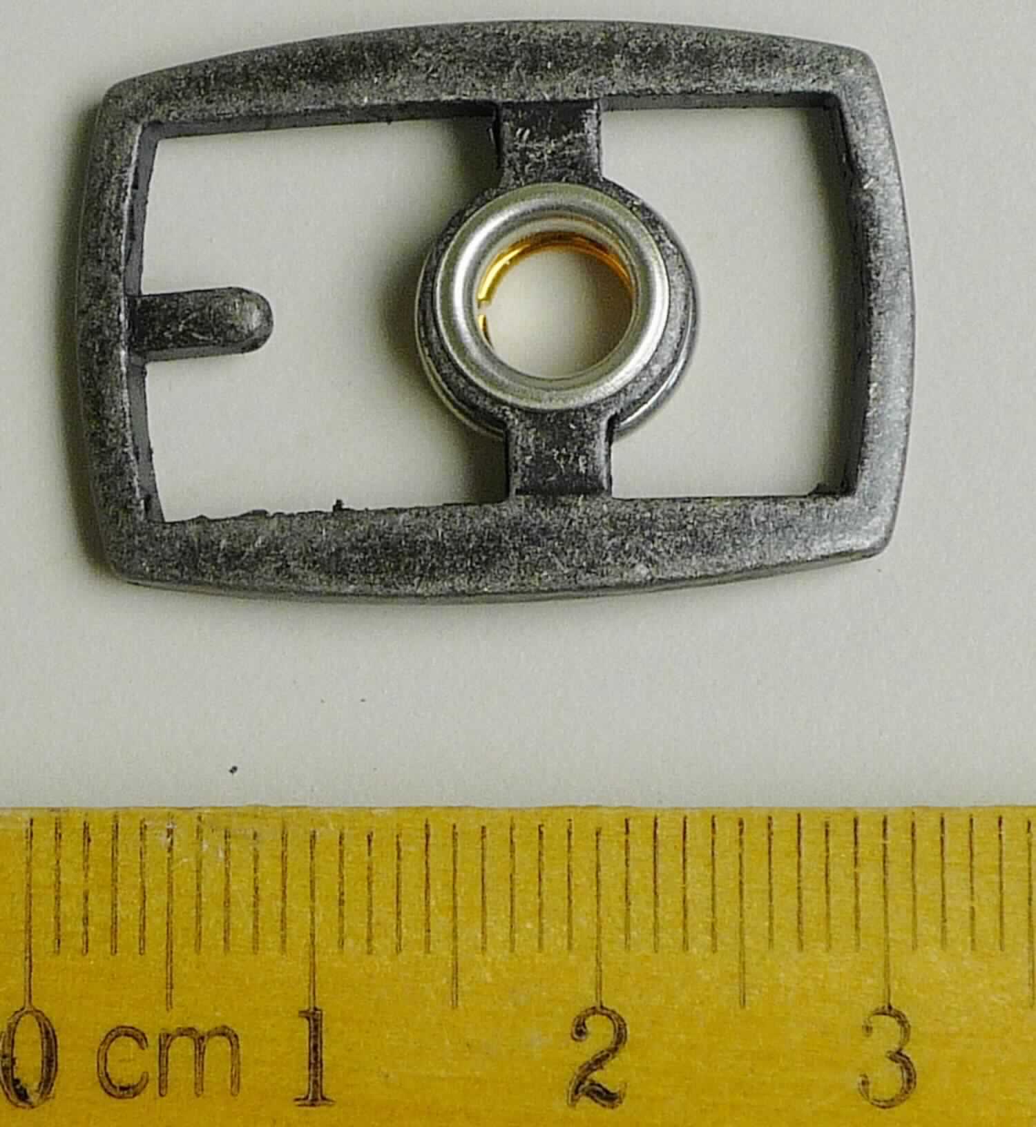 Bei der aus gewalztem Stahl bestehenden Schnalle mit abgerundeten Ecken (Breite ca. 31 mm und Länge ca. 30 mm) handelt es sich um ein erkennbares Teil eines Druckknopfs, der als Schuhverschluss eingesetzt wird.

Die Ware wird als erkennbares Teil eines Druckknopfs eingereiht.