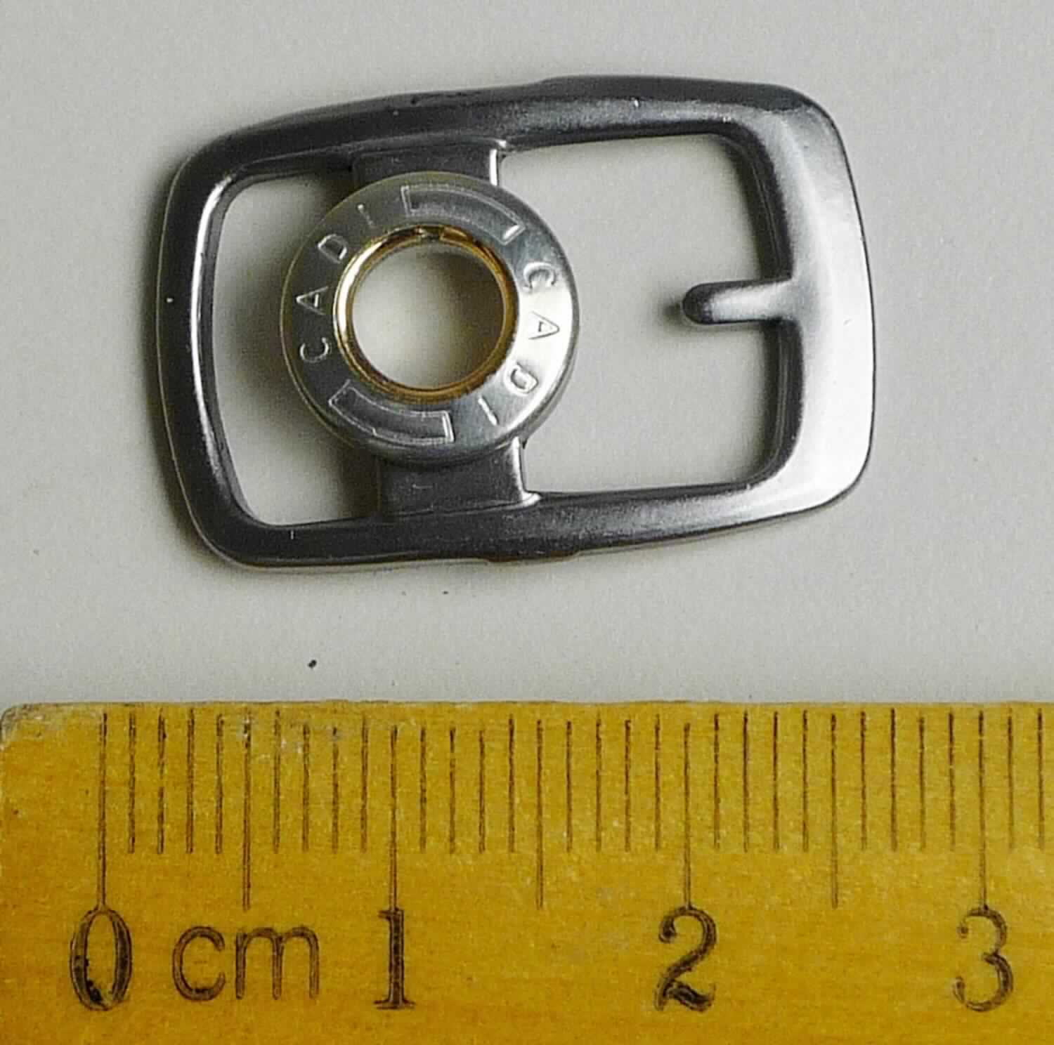 Bei der aus gewalztem Stahl bestehenden Schnalle mit abgerundeten Ecken (Breite ca. 17 mm und Länge ca. 25 mm) handelt es sich um ein erkennbares Teil eines Druckknopfs, der als Schuhverschluss eingesetzt wird.

Die Ware wird als erkennbares Teil eines Druckknopfs eingereiht.