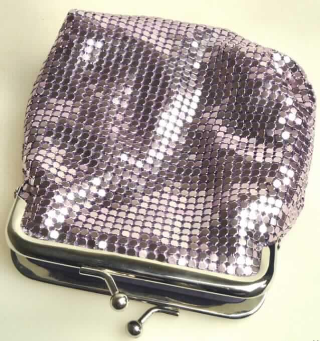 Taschen- oder Handtaschenartikel, Geldbörse, sog. Glitzer - Täschchen, Abbildung siehe 
Anlage, 
- Korpus aus zwei einfarbigen Spinnstofflagen (charakterbestimmend) mit einer Zwischenlage 
  aus Schaumstoff, 
- mit einer Außenseite aus verketteten, lilafarbenen Metallplättchen, 
- mit den Abmessungen von ca. 12 x 10 x 3 cm, 
- mit einem Bügelknopfverschluss an der Oberseite aus unedlem Metall, 
- innen keine weitere Einteilung, gefüttert, 
- keine Hinweise auf Handarbeit.

"Taschen- oder Handtaschenartikel, mit einem Taschenkorpus aus Spinnstoffen und einer 
Außenseite aus Metallplättchen, nicht handgearbeitet"