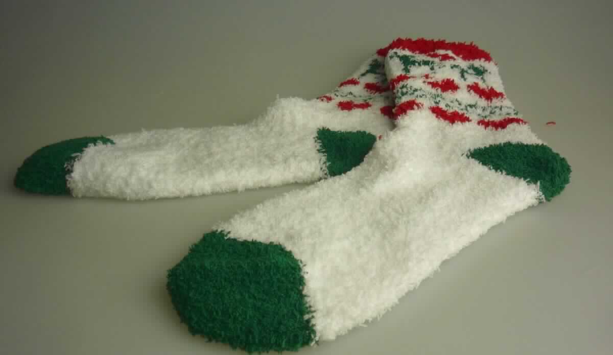 Socken, sog. Kuschelsocken Weihnachtsmotive, Art.Nr. 705 494, in Erwachsenengröße, Foto siehe Anlage,
- aus bis zu 4,2 mm dicken, buntgewirkten Gewirken aus laut Antrag 97 % Polyester und 3 % Elasthan (beides 
  synthetische Chemiefasern),
- schlauchförmig abgepasst gewirkt und an der Fußspitze durch Zusammennähen konfektioniert,
- mit ausgearbeiteter Ferse,
- am oberen Ende mit einem eingezogenen elastischen Band,
- den Knöchel bedeckend, nicht bis zur Mitte der Waden reichend (somit kein Kniestrumpf bzw. Strumpf für 
  Frauen),
- aufgrund des eigenen Gebrauchswertes als Socke kein Festartikel der Position 9505.

"Socken, aus Gewirken, aus synthetischen Chemiefasern"