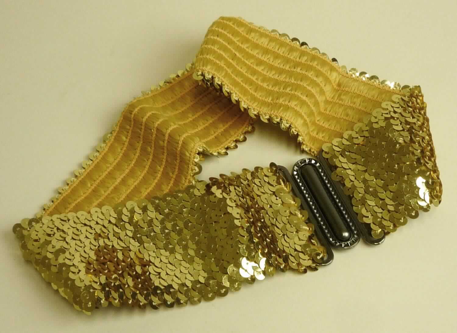Gürtel, sog. Paillettengürtel gold, Art. 22588.25, Foto siehe Anlage,
- in einem Polybeutel mit bedrucktem Pappaufhänger verpackt,
- aus einem gummielastischen Kettengewirke aus Spinnstoffen, mit eingearbeiteten Garnen, die mit Pailletten aus 
  augenscheinlich Kunststoff verziert sind,
- mit einer Gesamtlänge von ca. 60 cm und einer Breite von ca. 6 cm,
- mit einer Schnalle aus unedlem Metall,
- durch Zusammenfügen konfektioniert,
- wird als Ziergürtel um die Taille getragen,
- individuelles (selbstständiges) Einzelstück, das eine Ergänzung von Kleidung darstellt; wird als 
  Bekleidungszubehör nicht von der Position 6212 erfasst.

"Anderes konfekioniertes Bekleidungszubehör (Gürtel), aus gummielastischen Gewirken"