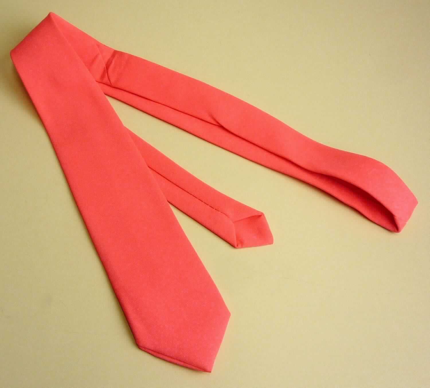 Krawatte, sog. Krawatte neonpink, Art. 22582.20, Foto siehe Anlage,
- in einem Polybeutel mit bedrucktem Pappaufhänger verpackt,
- aus ca. 0,4 mm dicken, einfarbigen Geweben aus laut Antrag 100 % Polyester (synthetische Chemiefasern),
- bis zu 7 cm breit und ca. 140 cm lang; an den Enden spitz zulaufend,
- zweilagig gearbeitet und mit einem Innenfutter ausgestattet,
- durch Zusammennähen konfektioniert,
- ohne Hinweise auf Handarbeit.

"Krawatte, aus Geweben, aus Chemiefasern, nicht handgearbeitet"