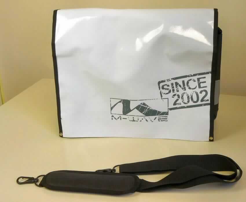 Aktentaschenähnliches Behältnis, sog. Messenger bag "M-Wave" (Art. 122380), Foto siehe Anlage, 
- mit einer Außenseite aus geprägten Kunststofffolien,
- in den Abmessungen: ca. 45 cm (Breite) x 35 cm (Höhe) x 14 cm (Tiefe).
- mit einem verstellbaren Schultertragegurt aus Spinnstoffen und einem Handtragegriff,
- mit einer über einen großen Teil der Vorderfront reichenden Überschlagklappe mit zwei 
  Klettverschlüssen,
- unter der Überschlagklappe mit zwei offenen Einsteckfächern,
- mit einem Hauptfach, 
- - unter der Überschlagklappe mit zwei magnetischen Druckknöpfen zu verschließen,
- - mit einem mit einem Klettriegel zu verschließenden, gepolsterten Laptopfach,
- - gefüttert,
- an den Schmalseiten jeweils mit zwei aufgenähten Reflektorstreifen aus Kunststofffolien,
- auf der Rückseite unter einer Überschlagklappe mit zwei magnetischen Druckknöpfen mit
  zwei Haken aus Kunststoffen zur Befestigung des Behältnisses an einem Fahrrad ausgestattet. 

"Aktentaschenähnliches Behältnis, mit Außenseite aus Kunststofffolien"