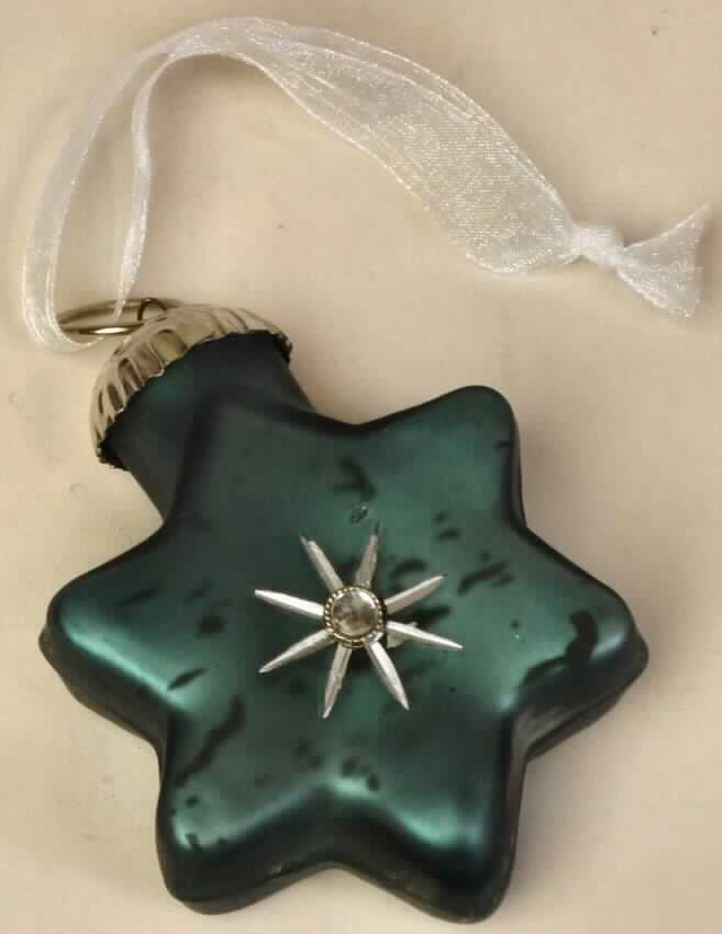 Glasware zur Innenausstattung, sog. Hänger Stern, Art. 4707800, Foto siehe Anlage, 
- in Form eines stilisierten, sechseckigen Sterns,
- aus (laut Antrag) gewöhnlichem Glas, farbig bemalt,
- auf einer Seite mit einem gefassten Strassstein verziert,
- ohne Hinweise auf manuelle Glasentnahme,
- am oberen Ende mit einer fest angebrachten Aufhängevorrichtung mit Öse aus unedlem Metall, 
  an der ein Band aus Spinnstoffen zum Aufhängen befestigt ist, 
- in den Abmessungen von bis zu ca. 6 x 2,5 x 8 cm,
- zu Dekorationszwecken bestimmt,
- keine Einreihung als Weihnachtsfestartikel in die Position 9505, weil ein eindeutiger Bezug zur 
  Advents- bzw. Weihnachtszeit fehlt.

"Glasware zur Innenausstattung, aus gewöhnlichem Glas, nicht handgefertigt"
