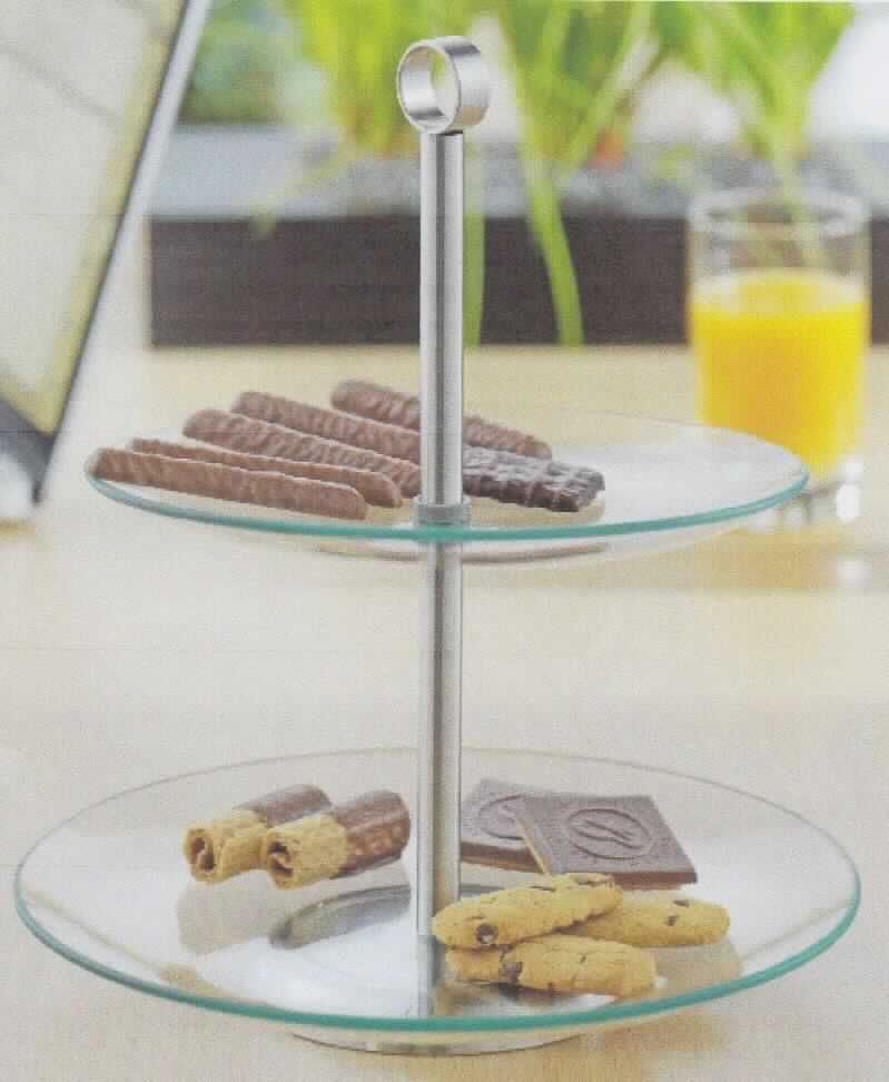 Glasware zur Verwendung bei Tisch oder in der Küche, sog. Glasetagére Cookie (Art. 199-618), Foto siehe Anlage,
aus verschiedenen Stoffen zusammengesetzte Ware, bestehend aus:
- zwei runden Platten aus gewöhnlichem, klarsichtigem Glas als Ablageflächen,
- - untere Platte (Durchmesser: ca. 25 cm) und obere Platte (Durchmesser: ca. 21 cm) sind 
   an der mittig durchlaufenden Metallstange angebracht,
- einer Halterung (Gestell) aus unedlem Metall (Stahl), 
- - bestehend aus einem runden Fuß und einer darauf angebrachten Stange, die am 
   oberen Ende mit einer ringförmigen Tragevorrichtung versehen ist,
- - mit einer Höhe von ca. 27 cm,
- das Glas bestimmt insbesondere nach dem Umfang und seiner Bedeutung in Bezug
  auf die Verwendung den wesentlichen Charakter der zusammengesetzten Ware,
- lt. Antrag handgefertigt (manuelle Glasentnahme).

"Glasware zur Verwendung bei Tisch oder in der Küche, kein Trinkglas, nicht aus Glaskeramik, 
 Bleikristall, Borosilikatglas oder vorgespanntem Glas, handgefertigt (manuelle Glasentnahme)"