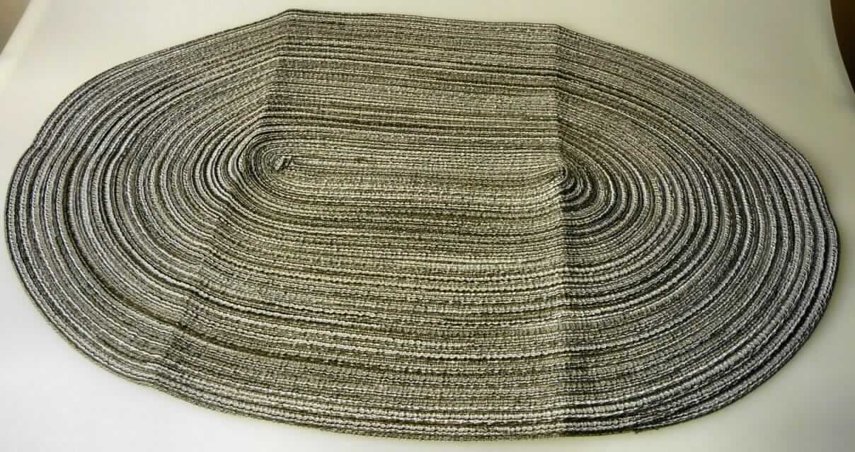 Tischwäsche, sog. Platzset, Foto siehe Anlage,
- in ovaler Form; in den Abmessungen: etwa 48,5 cm x 34 cm,
- aus einem flachen Geflecht der Position 5808 aus synthetischen Monofilen und aus Garnen aus laut Antrag 
  Polyester (synthetische Chemiefasern),
- spiralenförmig, teilweise überlappend zusammengenäht (damit konfektioniert), 
- wird laut Antrag üblicherweise gewaschen und kennzeichnet sich aufgrund des Materials und des 
  Verwendungszwecks als Tischwäsche.

"Tischwäsche, aus Spinnstoffen, aus Geflecht, aus Chemiefasern"