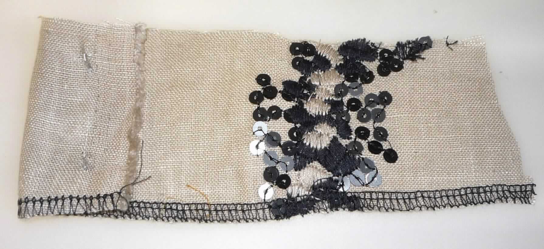 Stickerei als Meterware, sog. Bordino, Art. 2670, Foto siehe Anlage,
- als Meterware; lt. Antrag mit einer Breite von 130 cm,
- maschinelle Stickerei; keine Ätzstickerei oder Stickerei mit herausgeschnittenem Grund,
- mit einem Stickgrund aus ca. 0,3 mm dicken Geweben aus lt. Antrag Leinen sowie diesen Grund verzierenden 
  Stickfäden aus lt. Antrag Viskose (künstliche Chemiefasern) und Applikationen (Kunststoff-Pailletten),
- laut Antrag mit einem Wert von mehr als 17,50 EURO je kg Eigengewicht.


"Stickerei als Meterware, andere als in Unterposition 5810 10 genannte, aus Leinen, mit einem Wert von mehr als 
 17,50 EUR je kg Eigengewicht, nicht handgearbeitet"