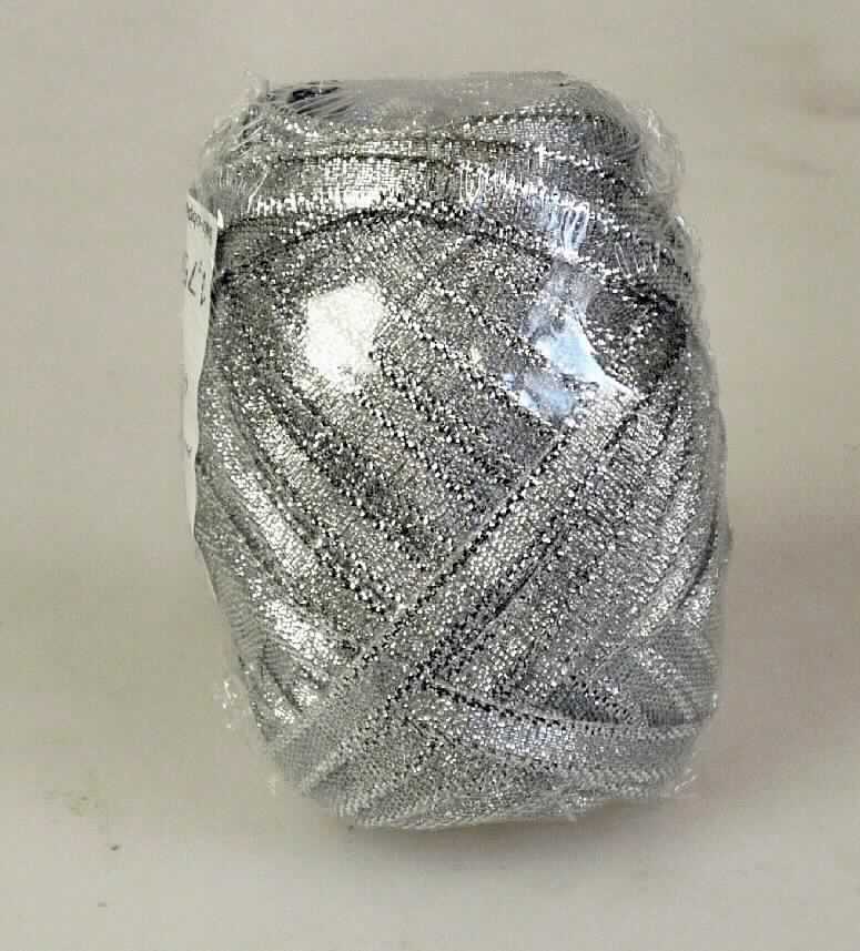 Band, sog. Eiknäuel, Art. 319-012, Foto siehe Anlage,
- als Meterware mit einer Länge von laut Antrag 10 m; als Knäuel in einer Kunststoffhülle verpackt,
- laut Untersuchungsergebnis:
-- mit einer Breite von ca. 0,5 cm,
-- aus einem Gewebe mit Kettfäden aus synthetischen Chemiefasern (Monofilen) und metallisierten Streifen aus 
   synthetischer Spinnmasse und Schussfäden aus metallisierten Garnen (ca. 1 mm breite, metallisierte Streifen 
   aus synthetischer Spinnmasse, die kreuzweise mit zwei Monofilen umwickelt sind),
-- mit einem Anteil an synthetischen Chemiefasern von 47,4 GHT und an metallisierten Garnen von 52,6 GHT,
-- mit echten Webkanten an beiden Längsseiten,
-- keine Elastomergarne oder Kautschukfäden enthaltend.

"Band, keine Ware der Position 5807, kein Samt, Plüsch, Chenille- oder Schlingengewebe, keine Elastomergarne 
 oder Kautschukfäden enthaltend, aus metallisierten Garnen"