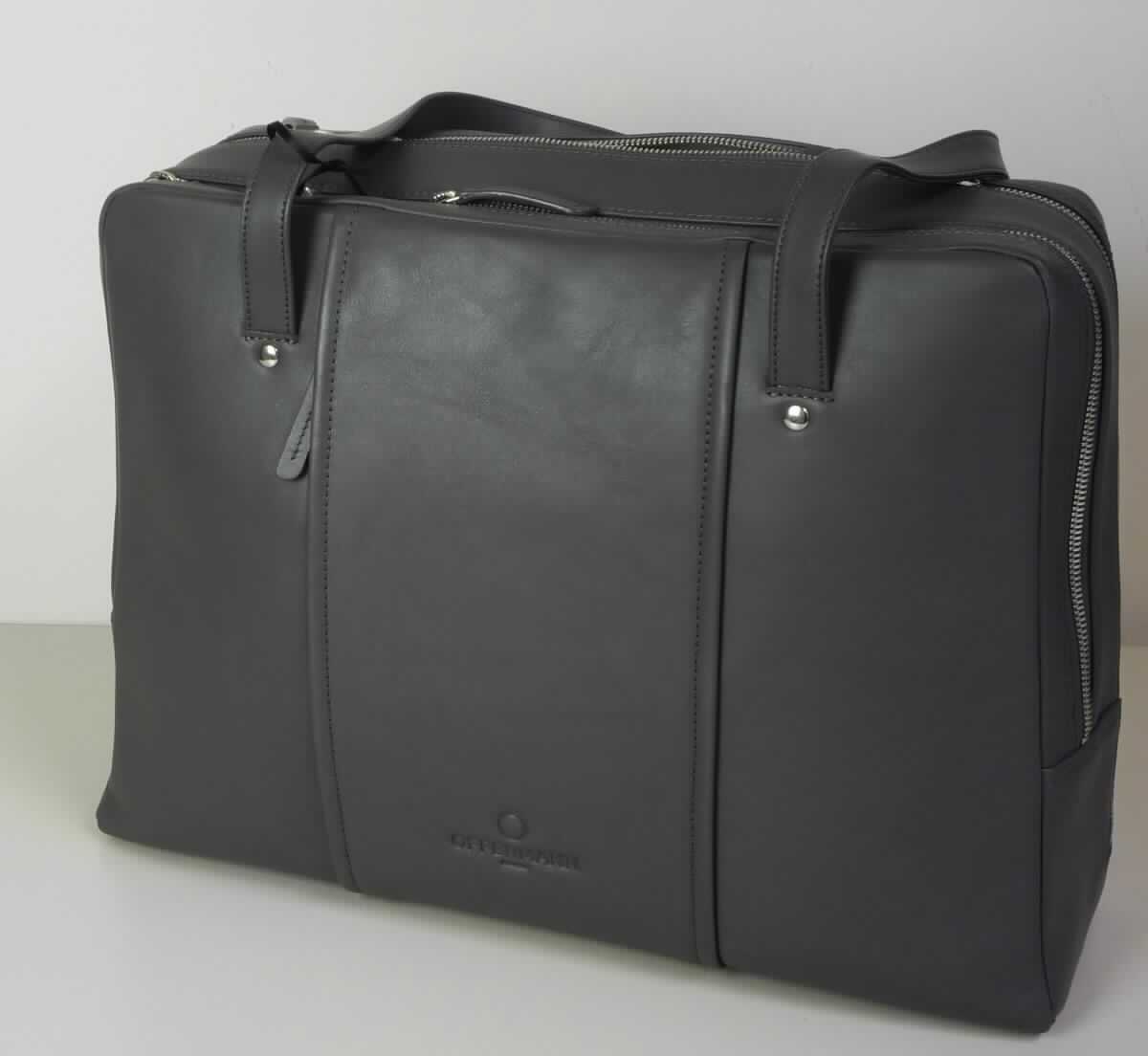 Aktentasche, sog. Day Bag - Damen-Businesstasche, Foto siehe Anlage,
- gemeinsam mit einem einfachen Beutel aus Spinnstoffen für den Einzelverkauf aufgemacht (der Beutel ist in
  die Aktentasche eingelegt); der Beutel ist geringwertig und im Hinblick auf die Verwendung als unbedeutend
  zu betrachten, er ändert das Wesen der Hauptware nicht und ist deshalb wie diese einzureihen,
- mit einer Außenseite aus Leder,
- mit zwei Tragegriffen, 
- auf einer Seite mit einem Vorfach mit einer seitlichen Öffnung mit Reißverschluss,
- mit zwei gefütterten Hauptfächern,
- - beide mit einem entlang der Schmalseiten und des oberen Rands verlaufenden Reißverschluss,
- - ein Hauptfach:
- - - auf einer Seite mit drei offenen Einsteckfächern und zwei Stiftlaschen, auf der anderen Seite mit einem
      Reißverschlussfach und einem abnehmbaren Lederriemen mit Karabinerhaken an den Enden ausgestattet,
- - ein weiteres Hauptfach:
- - - auf einer Seite mit großen, offenen Einsteckfach (z. B. zur Aufnahme eines Tablet-PCs) und am Boden
      mit drei längs verlaufenden, starren Stäben ausgestattet,  
- in den Abmessungen: ca. 40 cm (Breite) x 30 cm (Höhe) x 13 cm (Tiefe),
- ohne Hinweise auf Handarbeit.

"Aktentasche, mit Außenseite aus Leder, nicht handgearbeitet"
