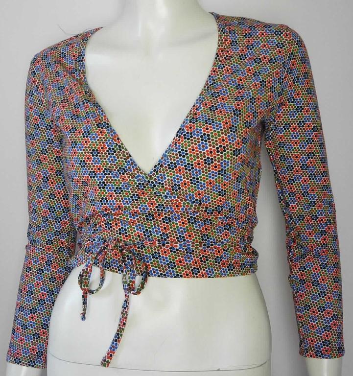 Bluse, sog. Strick Poly Croptop für Frauen, Art. RSA8394P, Größe S, Foto siehe Anlage,
- aus ca. 0,6 mm dicken (leichten), bedruckten Gewirken aus laut Antrag 95 % Polyester und 5 % Elasthan (beides
  synthetische Chemiefasern); mit durchschnittlich mehr als 10 Maschen in jeder Richtung je linearen Zentimeter,
- über die Taille reichend (Rückenlänge: ca. 42 cm),
- mit einem V-förmigen, sehr tiefen Halsausschnitt,
- mit langen Ärmeln,
- im Wickelstil gearbeitet, vorn mit einer durchgehenden Öffnung (u. a. somit keine Ware der Position 6109); 
  am Halsausschnitt und an den schräg gearbeiteten Vorderteilen mit einer zu Bindebändern auslaufenden 
  Randeinfassung; die Bindebänder werden durch eine kleine Öffnung in der Seitennaht (etwa 2 cm vom unteren 
  Rand) geführt und im Rücken oder vorn gebunden; mit Überlappung sowohl von rechts auf links als auch von links
  auf rechts (unisex), 
- am unteren Rand durch Umschlagen und Festnähen gesäumt,
- erfüllt die Merkmale zur Einreihung als Bluse (u. a. somit keine Ware der Position 6114).

"Bluse, aus Gewirken, für Frauen, aus Chemiefasern"