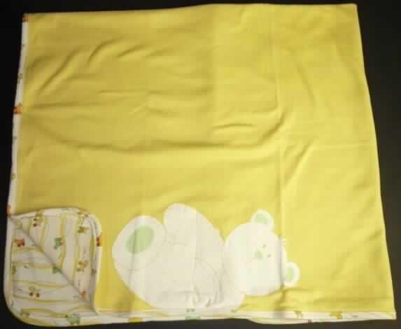 Decke, sog. Baby-Decke, siehe Foto
- rechteckig; in den Abmessungen: etwa 90 cm x 80 cm,
- aus 0,8 mm dicken, einfarbigen und buntbedruckten Gewirken aus laut Antrag
  100 % Baumwolle,
- an den Ecken abgerundet und ringsum mit einem Gewirkestreifen eingefasst,
- an einer Schmalseite auf dem einfarbigen Gewirke mit einem Aufdruck in Form eines
  stilisierten Bärens,
- ohne elektrische Heizvorrichtung,
- nicht gepolstert (somit keine Bettausstattung der Position 9404).