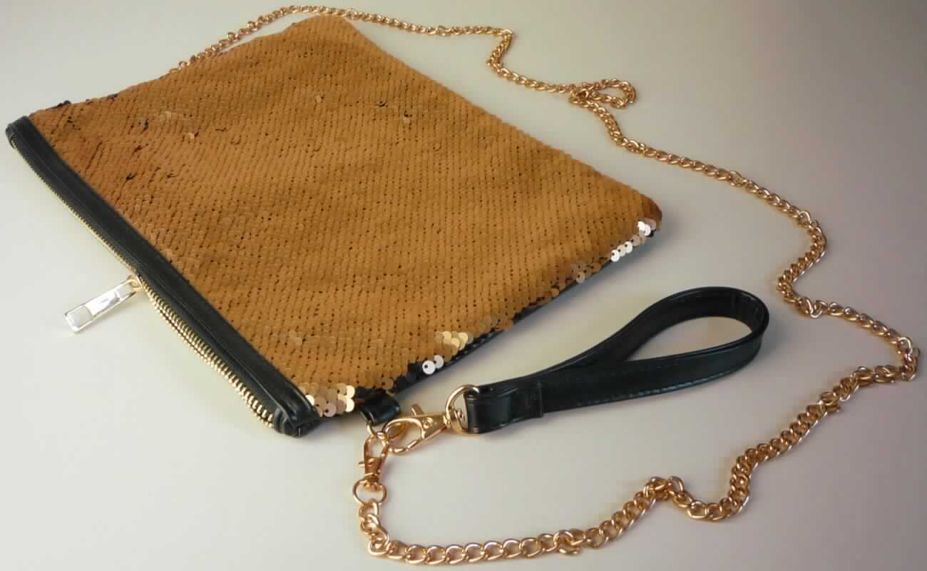 Handtasche, sog. zweifarbige, matte Pailletten-Tasche (Art. D3043Y77011AEN//17-1621), Foto siehe Anlage,
- mit einer Schauseite aus mit Pailletten bestickten Gewirken aus Spinnstoffen der Position 5810
  (Applikationsstickerei),
- - mit einer Außenseite aus Pailletten aus Kunststoff, die das Gewirke aus Spinnstoffen vollständig bedecken
    und den mit bloßem Auge wahrnehmbaren Stoff an der Oberfläche des Behältnisses bilden, 
- an der Rückseite mit einer Außenseite aus Kunststofffolien,
- die Kunststoffpailletten bestimmen nach dem äußeren Erscheinungsbild (Schauseite) den wesentlichen
  Charakter der Außenseite des Behältnisses,
- mit einer Handschlaufe und einer abnehmbaren Gliederkette aus unedlem Metall zum Tragen an der Schulter,
- am oberen Rand mit einem Reißverschluss,
- innen gefüttert und mit einem Fach mit Reißverschluss und zwei offenen Einsteckfächern ausgestattet,
- in den Abmessungen: ca. 26,5 cm (Breite) x 20,5 cm (Höhe) x 1 cm (Tiefe),
- aufgrund der Form, der Größe und des Gesamteindrucks in erster Linie dazu geeignet, kleinere persönliche
  Gegenstände aufzunehmen.

"Handtasche, mit einer anderen Außenseite als in den Unterpositionen 4202 2100 bis 4202 2290 genannte"