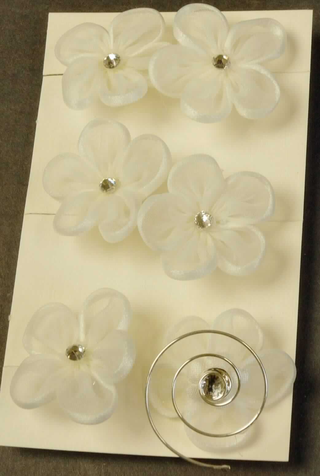 Es handelt sich um Haarschmuck in Form eines mit einer Spinnstoffblüte verzierten, spiralförmig gewundenen Drahtes aus unedlem Metall. Die naturweiße Blüte ist mittig mit einem Strassstein dekoriert.

Das in einer Kunststofftüte verpackte Erzeugnis (à 6 Stück) wird im Haar befestigt und als Haarschmuck verwendet.

Das Erzeugnis ist als "haarnadelähnliche Ware" einzureihen.