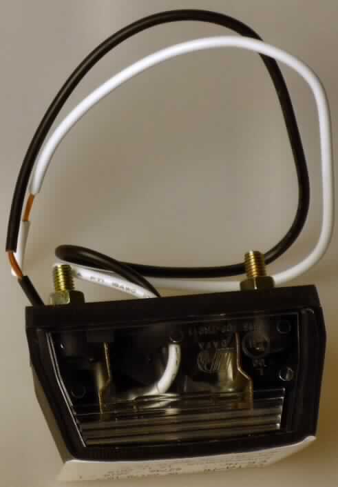 Kennzeichenleuchte,
- aus einer 12 V Glühlampe (Soffitenlampe) mit zwei Anschlusskabeln ohne 
  Anschlussstücke in einem spezifisch geformten Kunststoffgehäuse mit klarsichtiger 
  Lichtscheibe mit Reflektor und Montagevorrichtungen (Abbildung s. Anlage),
- nach Montage am Nummernschild und Anschluss an das Bordnetz eines Kraftfahrzeuges
  erkennbar zur Beleuchtung von Kraftfahrzeug-Kennzeichen bestimmt.

"Elektrisches Beleuchtungsgerät von der für Kraftfahrzeuge verwendeten Art - 
 Kennzeichenbeleuchtung."