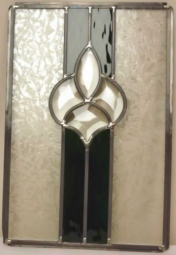 Kunstverglasung, sog. Möbelverglasung, Foto siehe Anlage,
- in Form einer Glasplatte, die aus Glasstücken besteht (in verschiedene Formen und Größen; zwei
  Glasstücke mit sog. Eisblumenmuster, vier Glasstücke grün gefärbt und vier Glasstücke klarsichtig
  und eingeschliffen in der Art von Antikglas), die durch Bleistege gefasst sind,
- an den Rändern ebenfalls durch Bleistege gefasst,
- in den Abmessungen: ca. 28 cm (Breite) x 41 cm (Höhe),
- wird lt. Antrag z. B. in eine Schranktür eingesetzt; kein Teil von Möbeln im Sinne der Positionen
  9401 bis 9403, da gesondert gestellte Platten aus Glas nicht als Teile gelten.

"Kunstverglasung"