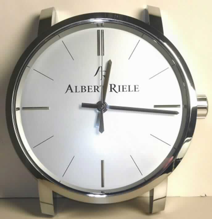 Bei der Ware handelt es sich um eine Wanduhr für den Innenbereich aus Kunststoff, einer runden Armbanduhr ohne Armband nachempfunden, mit einem Durchmesser von ca. 430 mm und einer Dicke von ca. 85 mm. Die Wanduhr besteht aus einem batteriebetriebenen Uhrwerk (kein Kleinuhr-Werk), das in einem ca. 55 mm x  55 mm x 15 mm großen Gehäuse untergebracht ist, einem Stunden-, Minuten- und Sekundenzeiger sowie einem runden Zifferblatt. 

Die in einem stabilen Pappkarton verpackte Ware ist als "andere als in den Positionen 9101 bis 9104 erfasste, elektrisch betriebene Wanduhr" einzureihen.