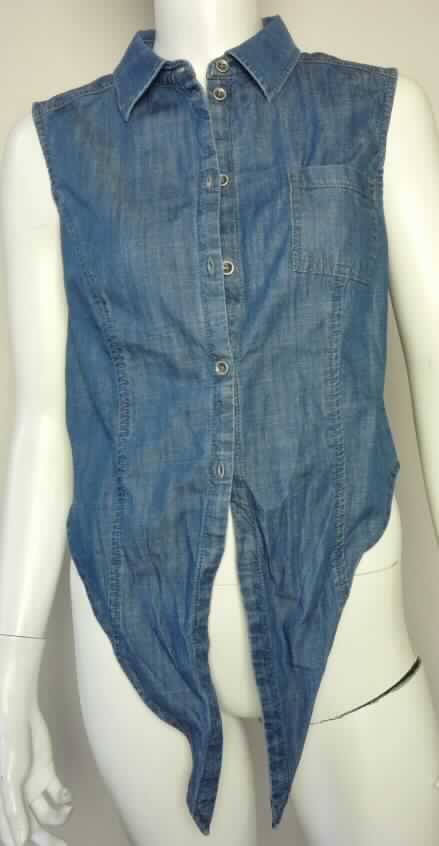 Bluse, sog. Damenbluse, Größe 36, Foto siehe Anlage,
- aus etwa 0,6 mm dicken (damit leichten), buntgewebten Geweben aus laut Antrag 100 % Baumwolle,
- bis über die Taille reichend (Rückenlänge: 45 cm),
- mit einem Umlegekragen,
- vorn mit einer durchgehenden Öffnung mit Knopfverschluss von rechts über links (Frauenkleidung),
- mit einer aufgesetzten Brusttasche,
- ärmellos, 
- mit nach unten verlängerten, spitz zulaufenden Vorderteilen, die miteinander verknotet werden können, aber 
  keine Verengung am unteren Rand darstellen,
- an den Armausschnitten und am unteren Rand durch Umschlagen und Festnähen gesäumt.

"Bluse, für Frauen, aus Geweben, aus Baumwolle, nicht nach dem Batik-Verfahren handbedruckt"
