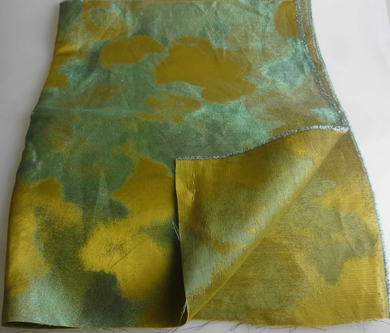 Jacquardgewebe, sog. Art. 2723 "Magnolia", Foto siehe Anlage,
- als Meterware; laut Antrag mit einer Breite von 140 cm,
- laut Untersuchungsergebnis:
-- buntgewebtes Jacquardgewebe,
-- aus Kettgarnen aus Seide und grünen, nicht hochfesten Schussgarnen aus künstlichen Filamenten (laut Antrag: 
   Viskose), hellgrauen Schussgarnen aus synthetischen Filamenten (laut Antrag: Polyester) und dunkelgrauen 
   Schussgarnen aus Leinen; mit einem Gesamtanteil an 
--- Viskose-Filamenten (künstliche Filamente) von 32 GHT,
--- Polyester-Filamenten (synthetische Filamente) von 7 GHT,
--- Seide von 31 GHT und
--- Leinen von 30 GHT (die Antragsangaben können als zutreffend angesehen werden).

"Gewebe aus Garnen aus künstlichen Filamenten, anderes als in den Unterpositionen 5408 10 bis 5408 24
 genannte, buntgewebt"