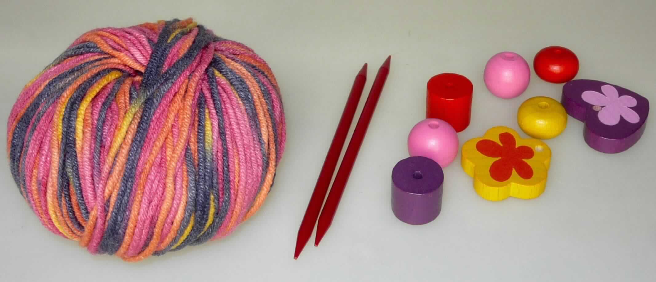 Handarbeitsset, Foto siehe Anlage,
- Warenzusammenstellung, bestehend aus einem Knäuel Garn, zwei Stricknadeln und verschiedenen Holzperlen;
  lt. Antrag gemeinsam in einem Pappkarton für den Einzelverkauf aufgemacht und zur Befriedigung eines 
  speziellen Bedarfs (Herstellung einer Halskette) zusammengestellt,
- Garn:
-- im Knäuel, lt. Antrag mit einem Gewicht von 25 Gramm und einer Länge von 70 m,
-- aus lt. Antrag 50 % Baumwolle und 50 % Polyacryl (synthetische Chemiefasern; lt. Antrag Spinnfasern),
-- gezwirnt; mit S-Drehung als letzter Drehung (u. a. somit kein Nähgarn),  
-- mit einem Titer von ca. 3571 dtex, somit kein Bindfaden,
-- in Aufmachung für den Einzelverkauf,
- zwei Stricknadeln:
-- augenscheinlich aus Kunststoff, mit einem Durchmesser von ca. 4 mm,
-- an beiden Seiten angespitzt,
- Holzperlen:
-- ein "Herz", eine "Blume" und sechs verschiedenfarbige "Perlen" in unterschiedlichen Formen, aus Holz; mit 
   Bohrung,
- das Stricken des Endproduktes stellt keine spielerische Basteltätigkeit dar, somit keine Ware der Position 9503,
- insbesondere im Hinblick auf die Bedeutung im Bezug auf die Verwendung verleiht das Garn der 
  Warenzusammenstellung ihren wesentlichen Charakter.

"Garn aus synthetischen Spinnfasern, kein Nähgarn, in Aufmachung für den Einzelverkauf, mit einem Anteil
 an synthetischen Spinnfasern von weniger als 85 GHT"