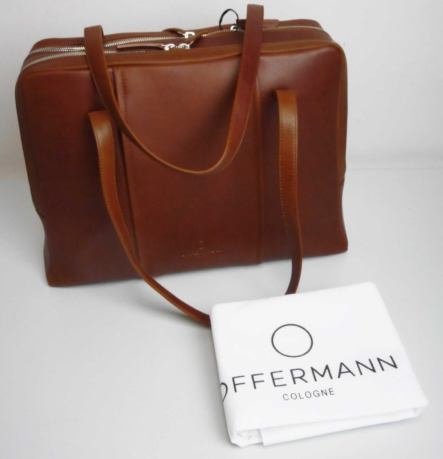 Aktentasche, sog. Damen-Businesstasche, Foto siehe Anlage,
- gemeinsam mit einem einfachen Beutel aus Spinnstoffen für den Einzelverkauf aufgemacht (der Beutel ist in
  die Aktentasche eingelegt); der Beutel ist geringwertig und im Hinblick auf die Verwendung als unbedeutend
  zu betrachten, er ändert das Wesen der Hauptware nicht und ist deshalb wie diese einzureihen,
- mit einer Außenseite aus Leder,
- mit zwei Tragegriffen, 
- auf einer Seite mit einem Vorfach mit einer seitlichen Öffnung mit Reißverschluss,
- mit zwei gefütterten Hauptfächern,
- - beide mit einem entlang der Schmalseiten und des oberen Rands verlaufenden Reißverschluss,
- - ein Hauptfach:
- - - auf einer Seite mit drei offenen Einsteckfächern und zwei Stiftlaschen, auf der anderen Seite mit einem
      Reißverschlussfach und einem abnehmbaren Lederriemen mit Karabinerhaken an den Enden ausgestattet,
- - ein weiteres Hauptfach:
- - - auf einer Seite mit einem großen, offenen Einsteckfach (z. B. zur Aufnahme eines Tablet-PCs) und 
       am Boden mit drei längs verlaufenden, starren Stäben ausgestattet,  
- in den Abmessungen: ca. 40 cm (Breite) x 30 cm (Höhe) x 13 cm (Tiefe),
- ohne Hinweise auf Handarbeit.

"Aktentasche, mit Außenseite aus Leder, nicht handgearbeitet"