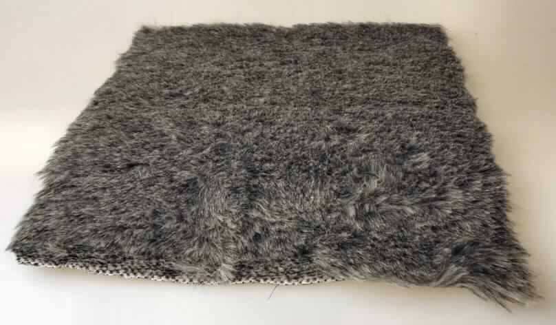 Textillaminat, Foto siehe Anlage,
- als Meterware; mit einer Breite von mehr als 30 cm,
- aus zwei mit ihrer ganzen Fläche aufeinanderliegenden und so miteinander durch Kleben verbundenen Lagen, 
- laut Untersuchungsergebnis bestehend aus:
-- einer Florseite, lt. Antrag die Schauseite bildend,
--- aus einem etwa 1,5 cm dicken Hochflorerzeugnis / Plüschgewirke, mit einem Flor aus Polyester- und
    Polyacrylspinnfasern (synthetische Chemiefasern) und einem Grund aus synthetischen Chemiefasern,
--- durch Wirken hergestellt, somit kein künstliches Pelzwerk der Position 4304,
-- einer Unterseite (glatte Seite),
--- aus einem ca. 0,4 mm dicken, gefärbten Gewebe aus Baumwolle,
---- in Leinwandbindung,
---- mit einem Quadratmetergewicht von weniger als 200 g,
- wird laut Antrag zum Herstellen von Schuhen verwendet,
- nach dem Umfang und dem Wert bestimmt das die Schauseite bildende Hochflorerzeugnis / Plüschgewirke 
  den Charakter der Ware.

"Plüsch ("Hochflorerzeugnis"), gewirkt, aus synthetischen Chemiefasern"