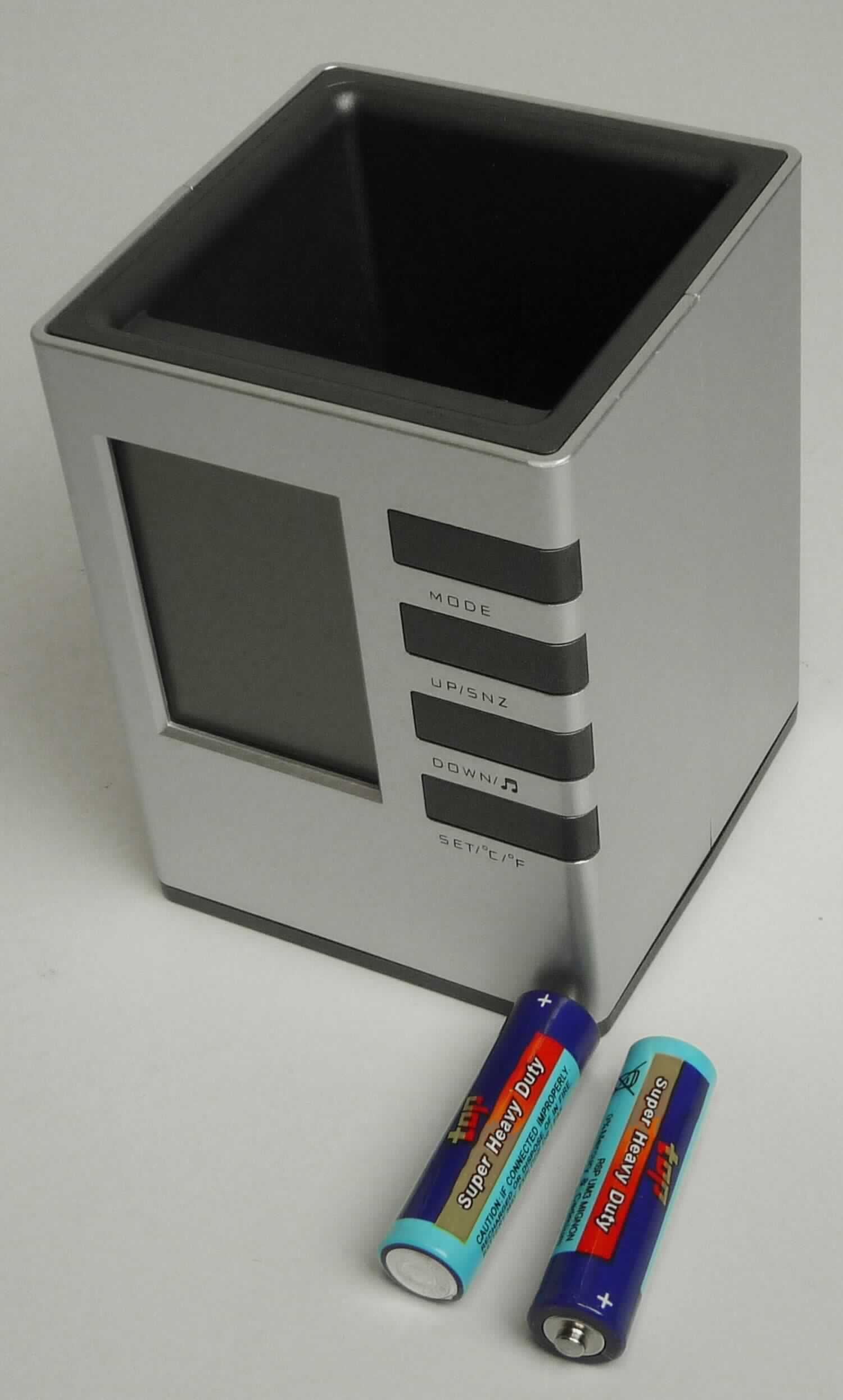Bei der LCD-Tischuhr einschließlich Stifteköcher "Desk Set 2000", Artikel-Nr. 54010, handelt es sich um eine zusammengesetzte Ware, ca. 8 cm x 11 cm x 8 cm groß (Breite x Höhe x Tiefe), bestehend aus:
- einem oben offenen Kunststoffbehältnis zur Nutzung als Stiftehalter;
- einem elektrisch betriebenen Wecker (2 Batterien) mit digitaler Anzeige der Uhrzeit (Stunde und Minuten), des Datums und des Wochentages (Größe der Platine: 6,8 cm x 5,8 cm x 0,8 cm = Länge x Breite x Dicke; somit kein Kleinuhr-Werk i.S.d. Anmerkung 3 zu Kapitel 91), gemeinsam mit einem integrierten Thermometer (Anzeige der Innentemperatur in Grad Celsius und Grad Fahrenheit möglich). 
Neben der vorderseitigen Anzeigefläche befinden sich vier Funktionstasten; das Batteriefach befindet sich auf der Unterseite des Korpusses.

Ein charakterbestimmender Bestandteil hinsichtlich des Stiftehalters, der Uhr und des Thermometers ist nicht feststellbar. Die zusammengesetzte Ware ist deshalb von den gleichermaßen in Betracht kommenden Positionen der zuletzt genannten Position zuzuweisen.
 
Das Erzeugnis ist mit einer Bedienungsanleitung in einem Pappkarton verpackt.

Die zusammengesetzte Ware ist als "andere als in den Positionen 9101 bis 9104 erfasste Uhr, Wecker, elektrisch betrieben" einzureihen.