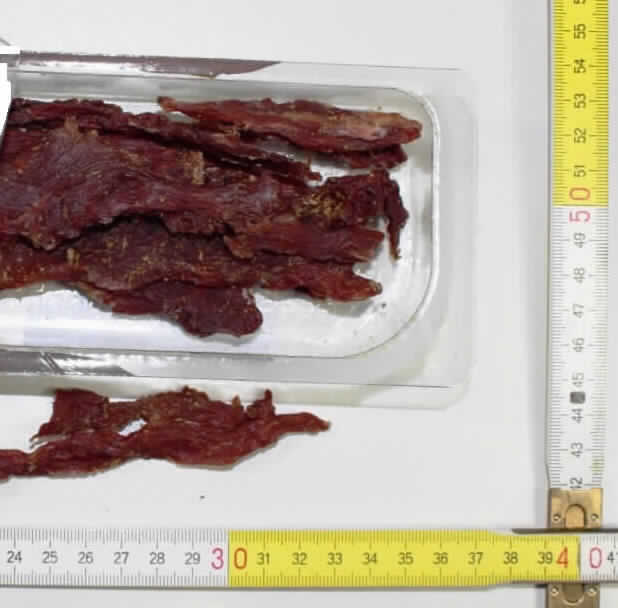 Getrocknete Rindfleischstreifen mit Käse-Raspeln

Angaben des Antragstellers:
Es soll sich laut vorgelegter Produktspezifikation um getrocknete, dunkelrote, feste, mit Gewürzen und sehr geringen Mengen Käse behandelte Rindfleischstreifen handeln, die a ca. 40-60 g in Kunststoffschalen mit bedrucktem Kunststofffoliendeckel unter Schutzgasatmosphäre verpackt sind. Die Handelsware soll auch ohne Kühlung 30 Tage nach Anlieferung haltbar sein.

Feststellung:
Vorgelegt wurde eine etikettierte Kunststoffschale mit ca. 60 g dunkelbraunen, festen, trockenen Streifen unterschiedlicher Form und Breite, auf deren Oberseiten sich helle Partikel befinden. Die Streifen schmecken und riechen nach getrocknetem Fleisch.

Befund:
Fleisch und genießbare Schlachtnebenerzeugnisse, gesalzen, in Salzlake, getrocknet oder geräuchert; genießbares Mehl von Fleisch oder von Schlachtnebenerzeugnissen / -Fleisch von Rindern / --ohne Knochen / ---anderes
