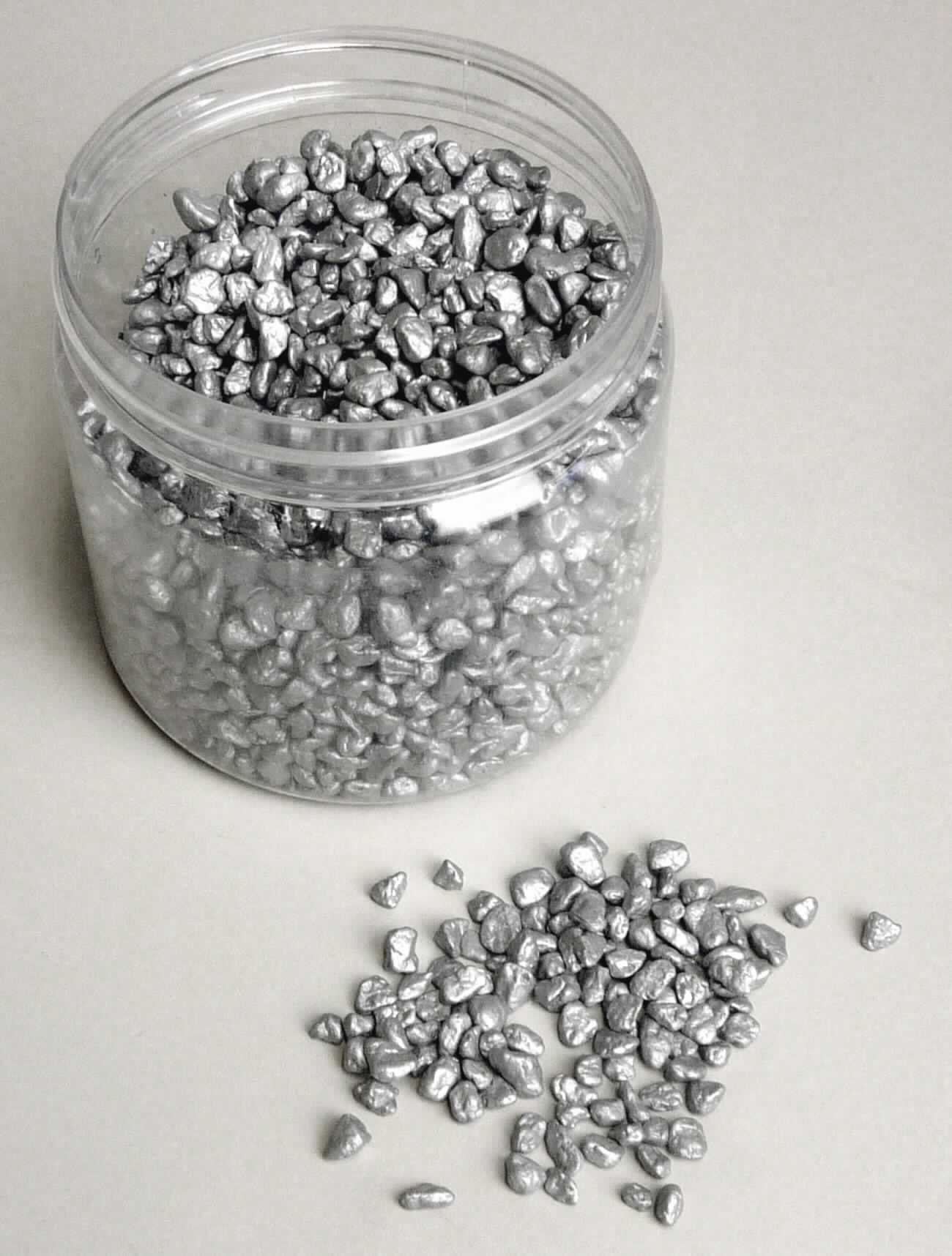 Angaben:
Dekosteine grau, glänzend; Material: Steine.

Warenbeschaffenheit:
silber-metallisch glänzendes, splittförmiges Stein-Granulat.

Befund:
Körnung von Naturstein, künstlich gefärbt