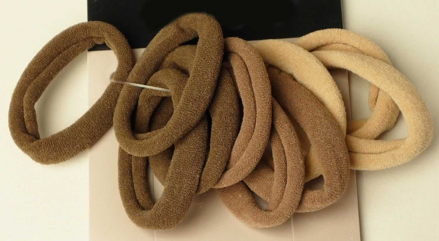 Gewirke, sog. Haargummis, Art. LAN 11448, Foto siehe Anlage,
- als zehnteiliges Sortiment auf einer bedruckten Pappkarte aufgebracht,
- jeweils:
-- bestehend aus einem einfarbigen, schlauchförmigen, aufgerollten Gewirke ohne Schlingen- oder Floroberfläche,
-- flachliegend mit einer Breite von bis zu ca. 3 cm,
-- laut Antrag aus 60 % Polyamid und 40 % Elasthan (Elastomergarn; beides synthetische Chemiefasern),
-- nur geschnitten (nicht konfektioniert).

"Gewirke mit einer Breite von weniger als 30 cm und mit einem Anteil an Elastomergarnen von mehr als 5 GHT,
 andere als solche der Position 6001, keine Kautschukfäden enthaltend, aus synthetischen Chemiefasern"