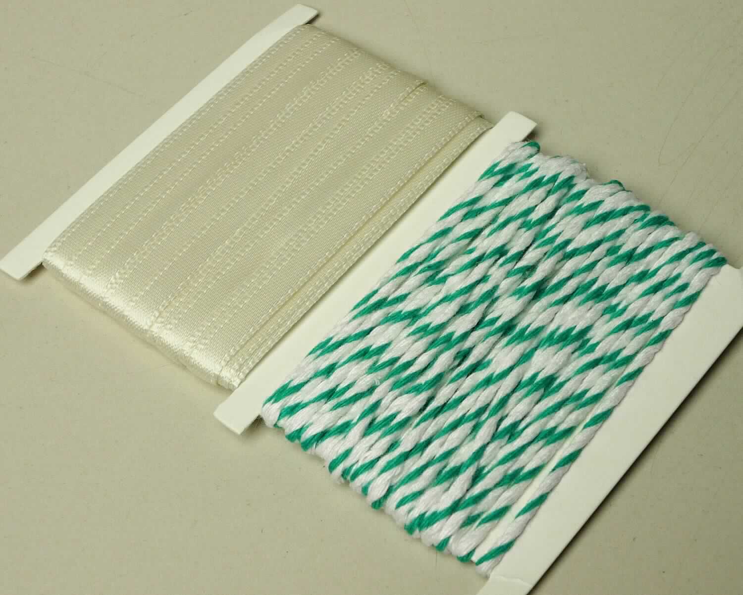 Satinband und Dekokordel, sog. Deko-Zubehör für Geschenkschachtel-Set, Art. XDEKO 974 00000, Foto siehe Anlage,
- stellt sich als Warenzusammenstellung dar, 
- gemeinsam in einem Polybeutel auf einer Pappunterlage für den Einzelverkauf aufgemacht und zur Befriedung 
  eines speziellen Bedarfs zusammengestellt,
- Band:
-- mit einer Breite von ca. 0,5 cm und einer Länge von laut Antrag 4 m,
-- aus einfabigen Geweben aus laut Antrag 100 % Polyester (synthetische Chemiefasern),
-- mit echten Webkanten an beiden Längsseiten, 
-- kein Samt, Plüsch, Chenille- oder Schlingengewebe,
-- keine Elastomergarne oder Kautschukfäden enthaltend,
- Kordel:
-- mit einer Länge von laut Antrag 4 m,
-- laut Antrag aus 100 % Baumwolle; augenscheinlich nicht appretiert (damit kein Nähgarn),
-- zweifarbig gezwirnt,
-- mit einem Gewicht von ca. 3,6 g (Garn in Aufmachung für den Einzelverkauf),
-- mit einem Titer von weniger als 20.000 dtex,
- im Hinblick auf den Wert, die Länge sowie die Bedeutung in Bezug auf die Verwendung sind das Band und die
  Kordel als gleich zu betrachten, damit kann keinem der beiden Stoffe eine charakterverleihende Eigenschaft 
  zuerkannt werden; die Warenzusammenstellung ist somit der von den gleichermaßen in Betracht kommenden 
  Positionen (5207 / 5806) in der Nomenklatur zuletzt genannten zuzuweisen.

"Band, keine Ware der Position 5807, andere als in den Unterpositionen 5806 10 und 5806 20 genannte, 
 aus Chemiefasern, mit echten Webkanten"
