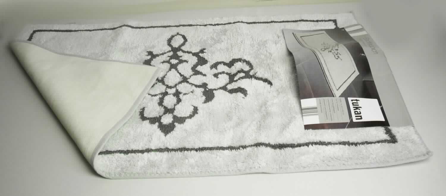 Fußbodenbelag, sog. Badematte "Royal", Foto siehe Anlage,
- laut Antrag in den Abmessungen: 60 cm x 90 cm,
- lt. Untersuchungsergebnis aus einem Plüschgewirke mit einem Flor aus Polyester (synthetische 
  Chemiefasern) sowie einem Grund aus Baumwolle und Polyester,
- mit einer rutschhemmenden Rückenbeschichtung versehen,
- an den Rändern mit einem Gewebeband eingefasst,
- durch Zusammenfügen konfektioniert, 
- ohne Hinweise auf Handarbeit.

"Fußbodenbelag, anderer als in den Positionen 5701 bis 5704 genannte, aus synthetischen Spinnstoffen,
 nicht handgearbeitet"
